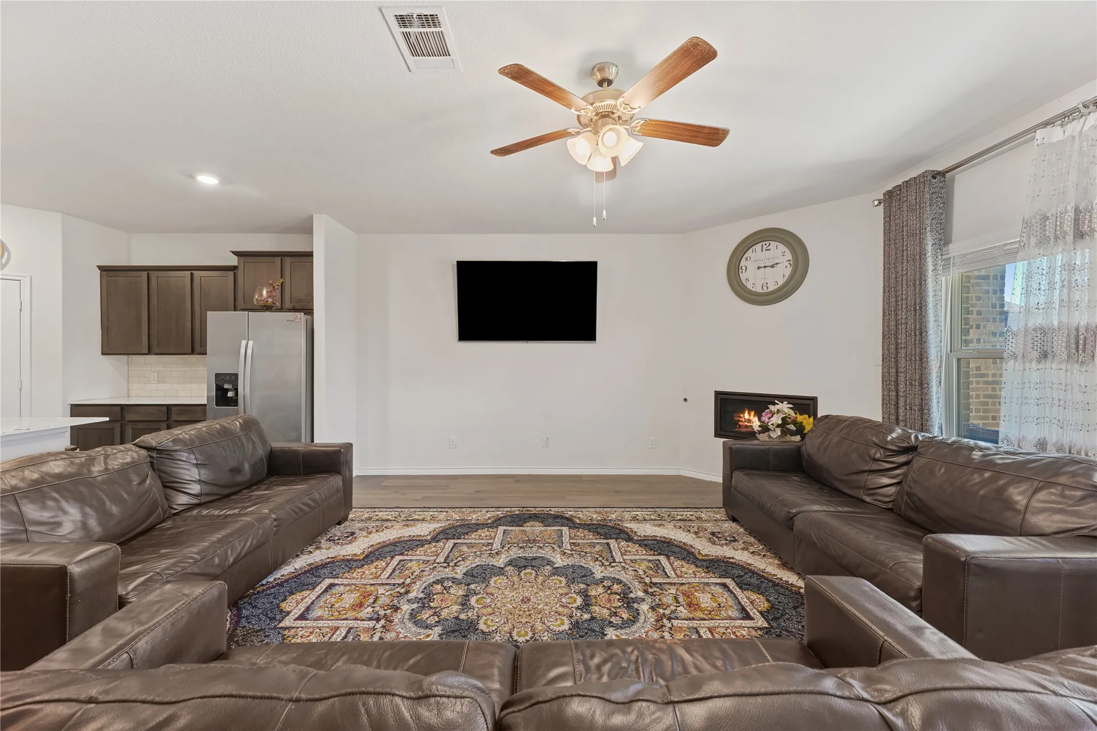 Wood-finish flooring, ceiling fan with integrated lighting, recessed lighting, and a built-in fireplace
