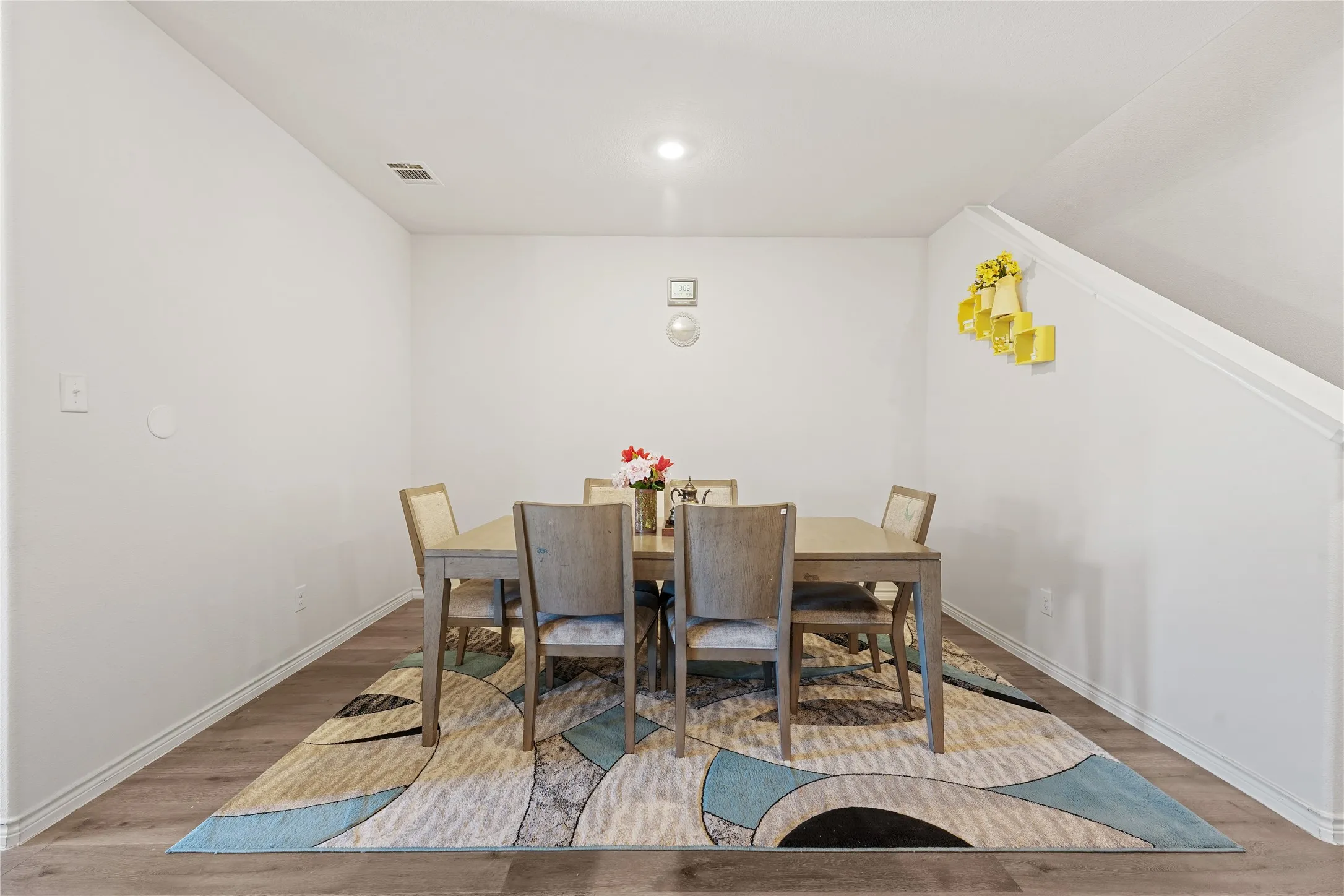 Wood-finish flooring with white baseboards, recessed ceiling lighting, and a sloped ceiling detail