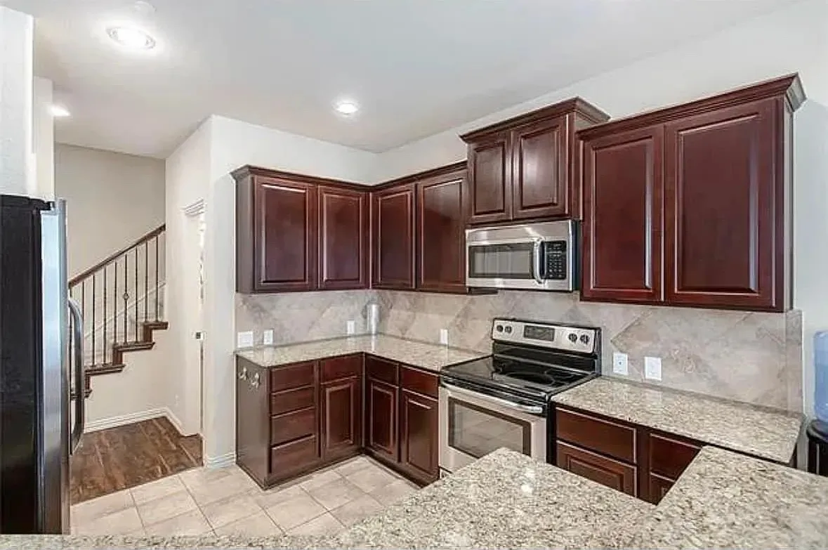 Kitchen featuring light tile patterned floors, backsplash, light stone countertops, and stainless steel appliances
