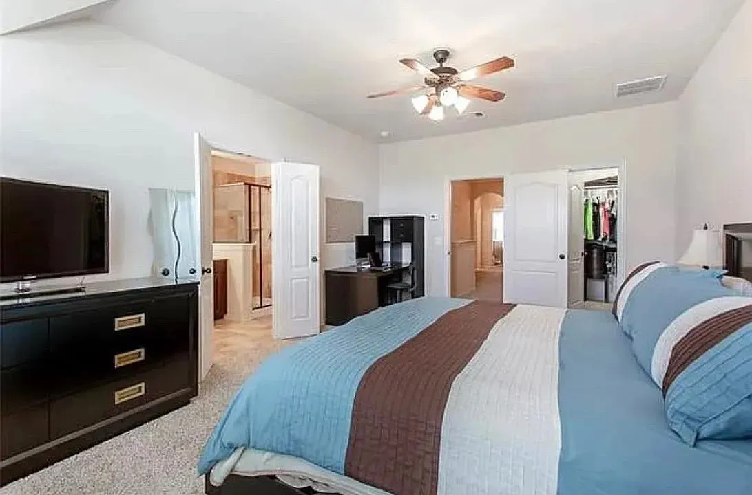Carpeted bedroom featuring a spacious closet, a closet, ceiling fan, and ensuite bath