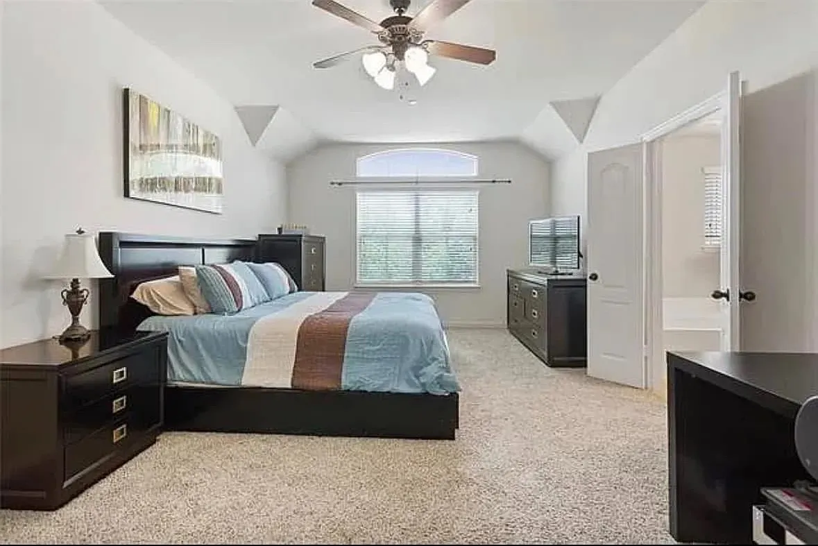 Carpeted bedroom with ceiling fan and lofted ceiling