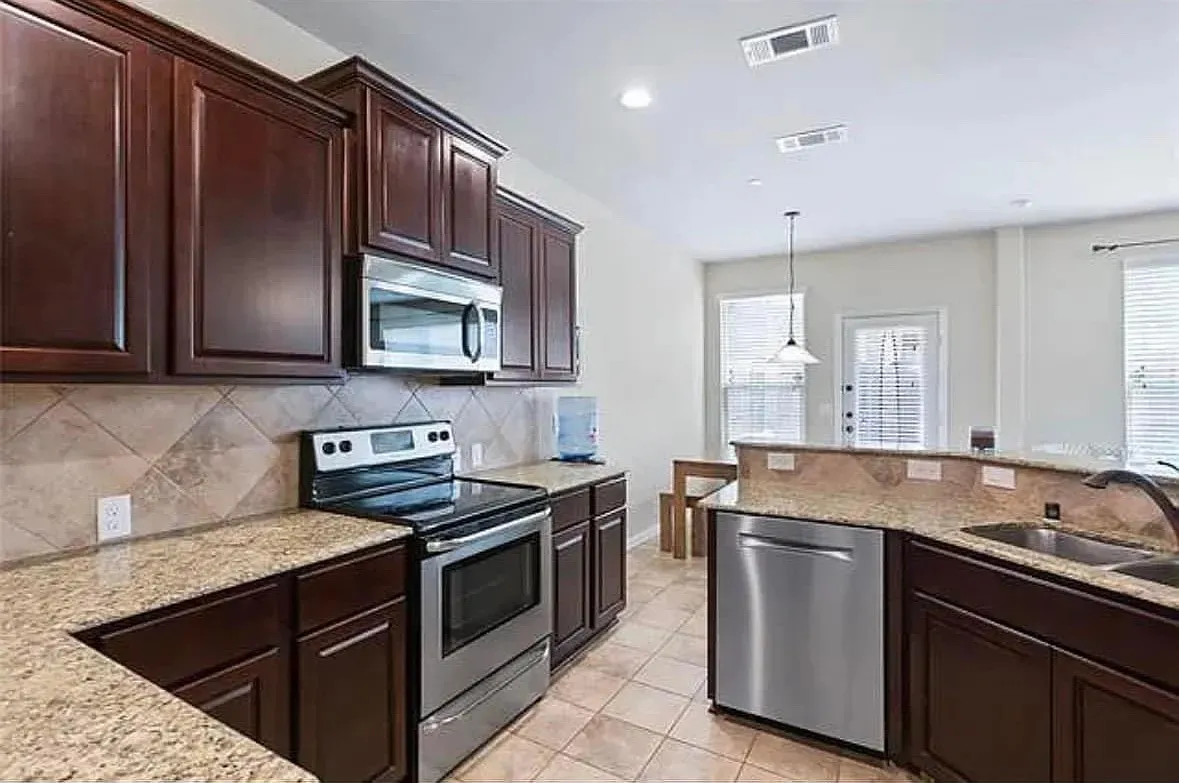 Kitchen featuring decorative light fixtures, decorative backsplash, sink, appliances with stainless steel finishes, and light tile patterned floors