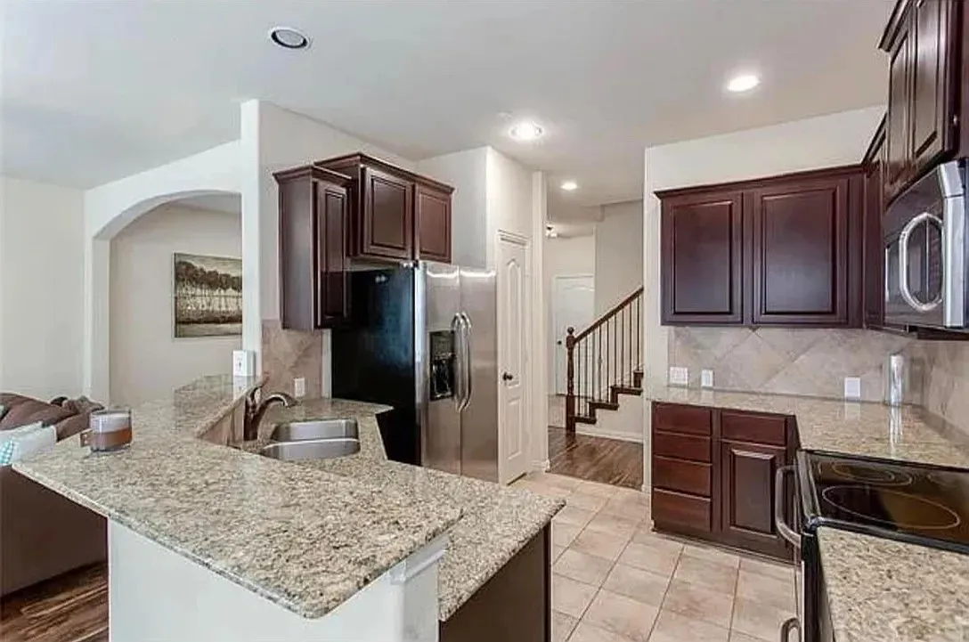 Kitchen featuring decorative backsplash, sink, light tile patterned flooring, stainless steel appliances, and light stone counters