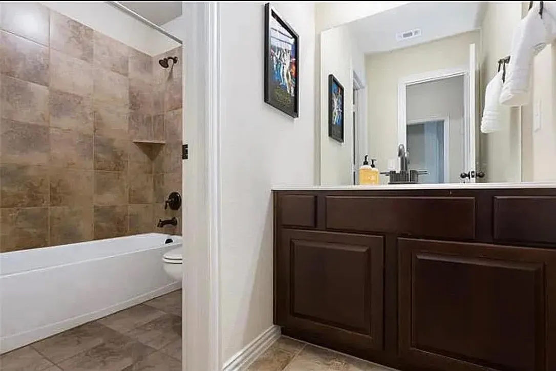 Full bathroom featuring toilet, tiled shower / bath combo, and vanity
