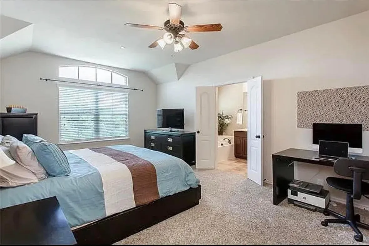 Bedroom with ceiling fan, ensuite bath, light carpet, and lofted ceiling