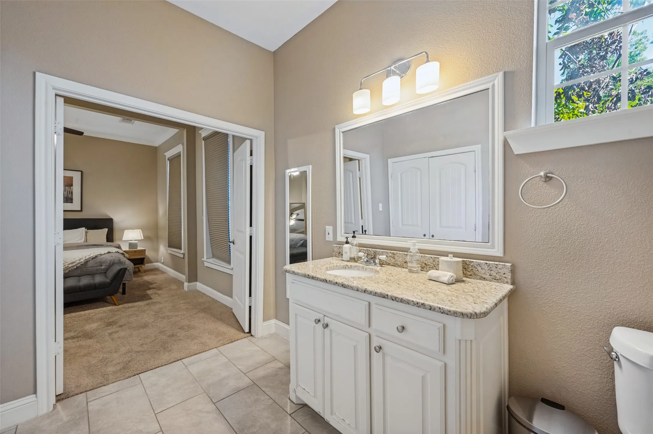 Bathroom vanity featuring a granite countertop, undermount sink, and white cabinetry