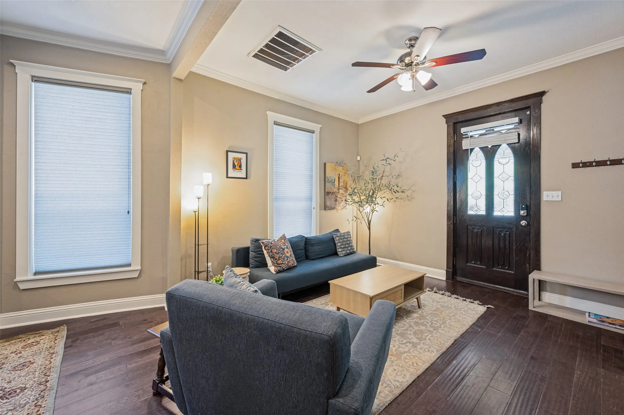 Wood-finish flooring, crown molding, and a ceiling fan with integrated lighting