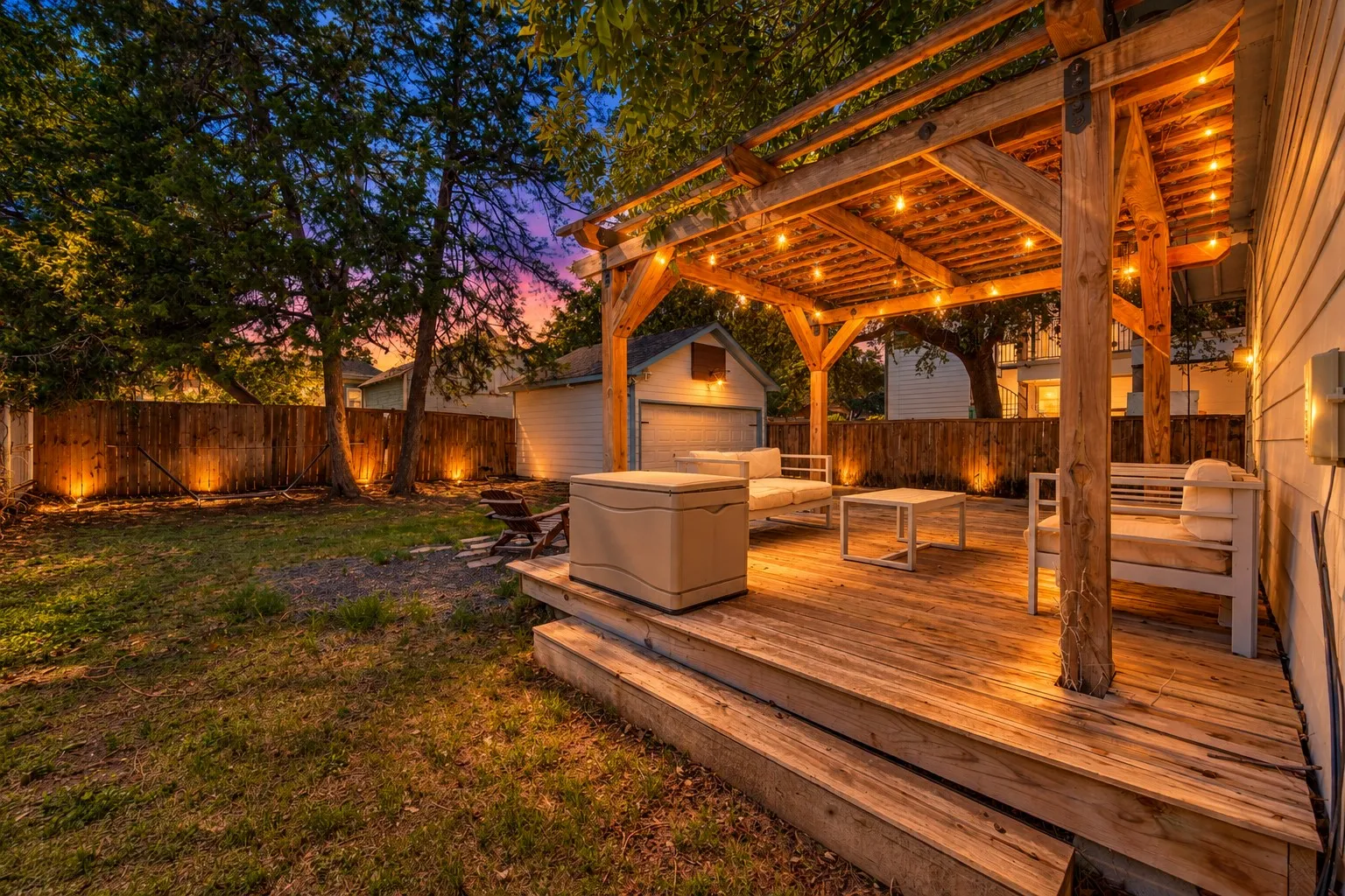Wood-finish deck with integrated steps, overhead wooden pergola, and string lighting
