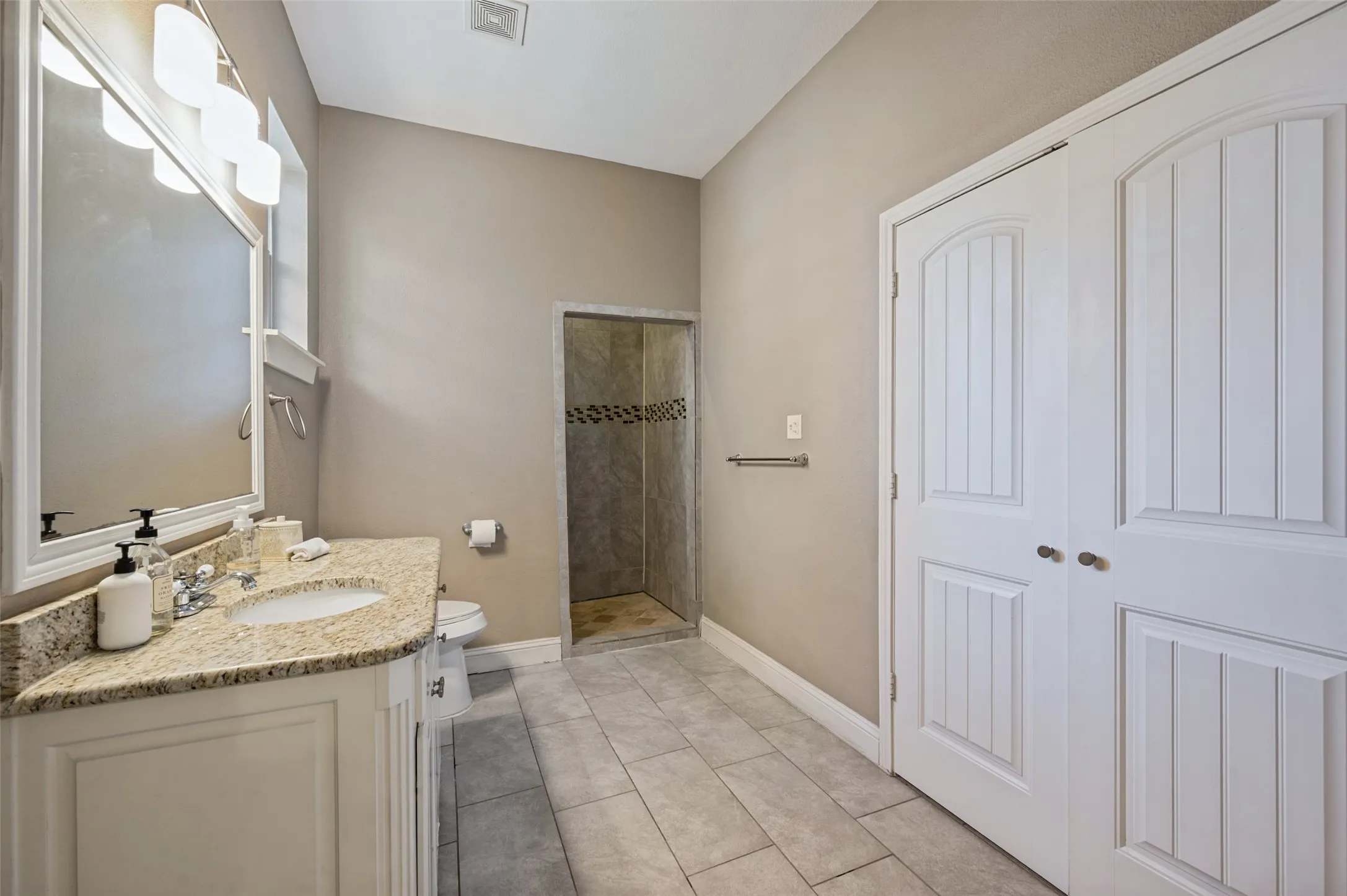 White vanity with an integrated sink, granite-style countertop, and chrome fixtures