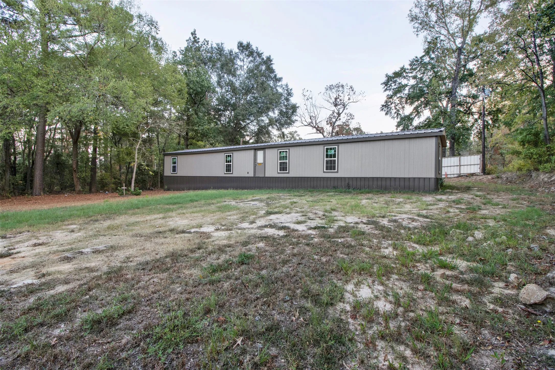 Two-tone exterior siding, multiple windows with dark trim, and a metal roof