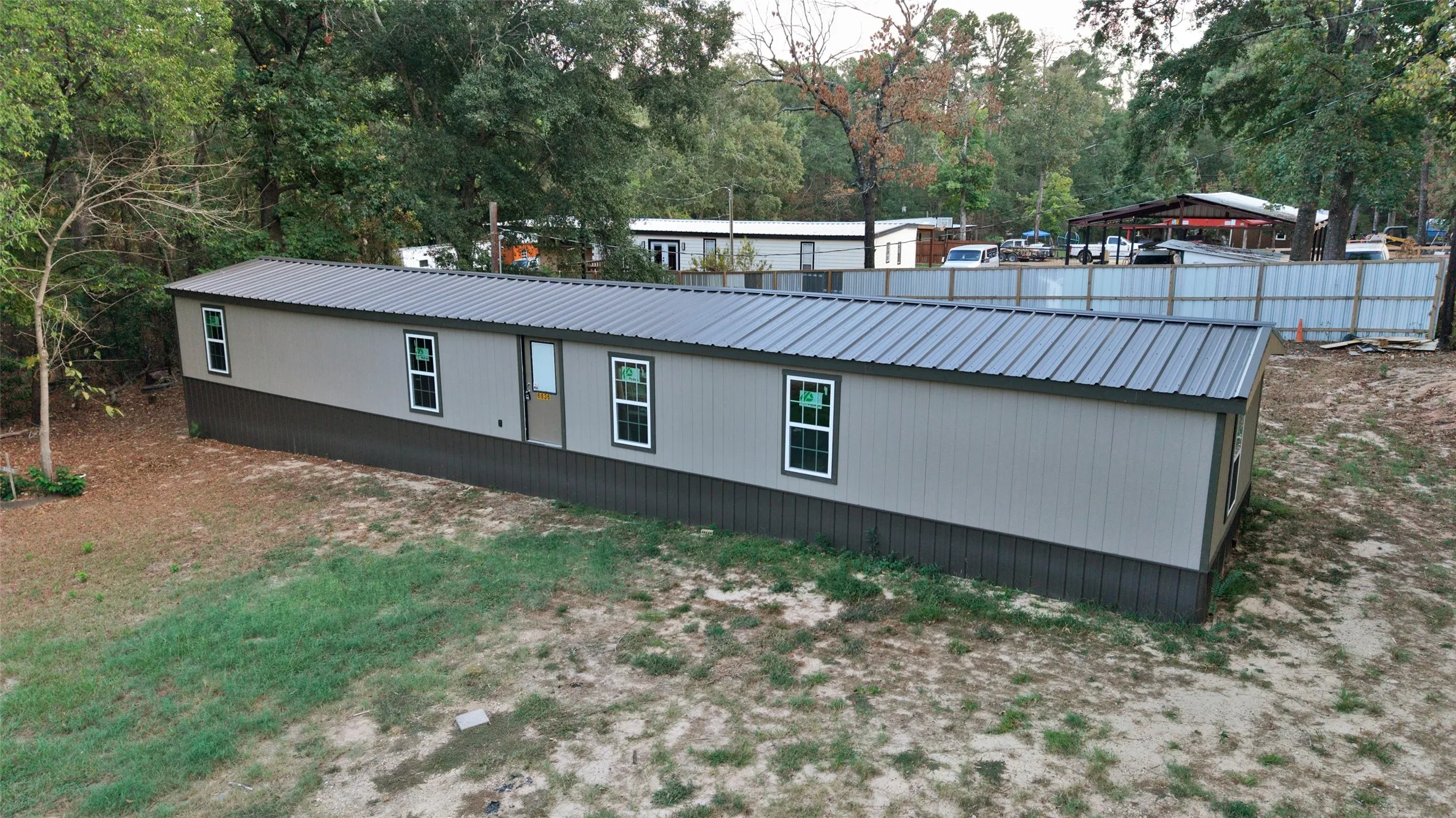 Two-tone exterior with light gray siding and dark gray trim, featuring a dark gray metal roof, multiple windows with white trim, and a prominent entry door
