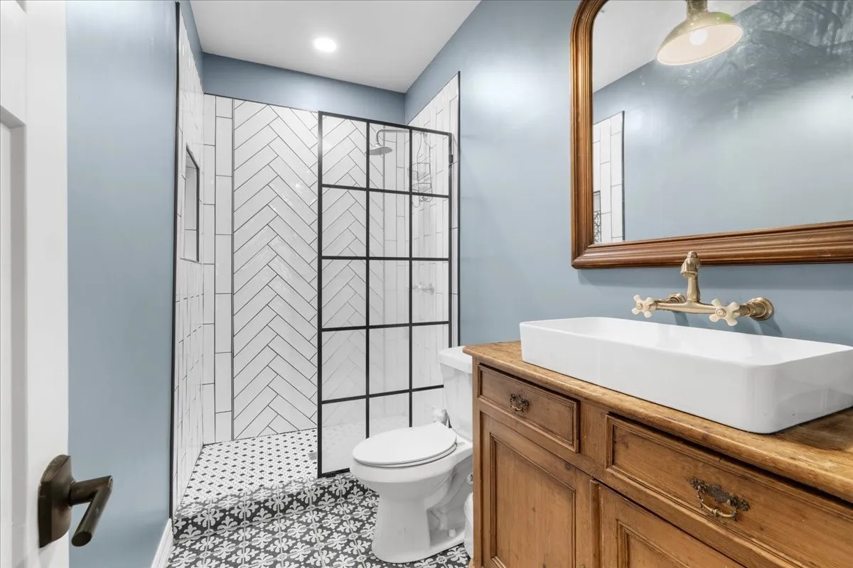 Walk-in shower with herringbone tile surround and grid-patterned glass enclosure