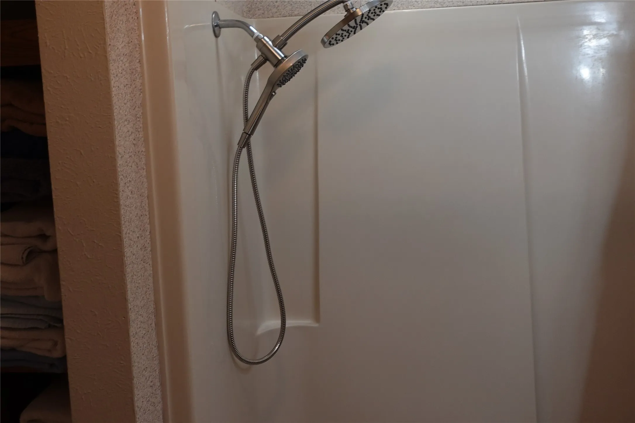 Shower enclosure featuring a fixed showerhead and an additional handheld shower fixture