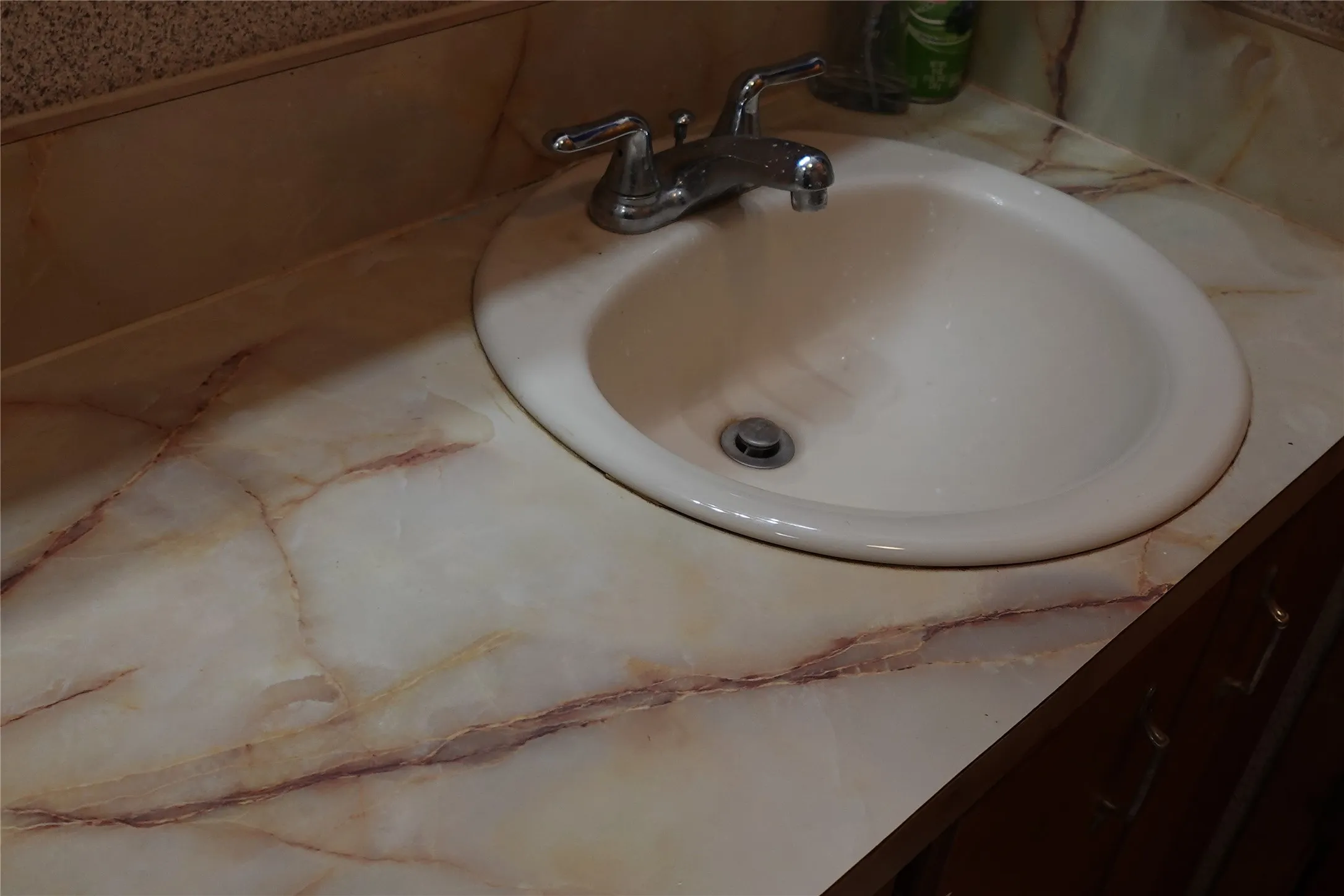 Vanity with an integrated oval sink and chrome faucet, featuring a marbled countertop with an integrated backsplash