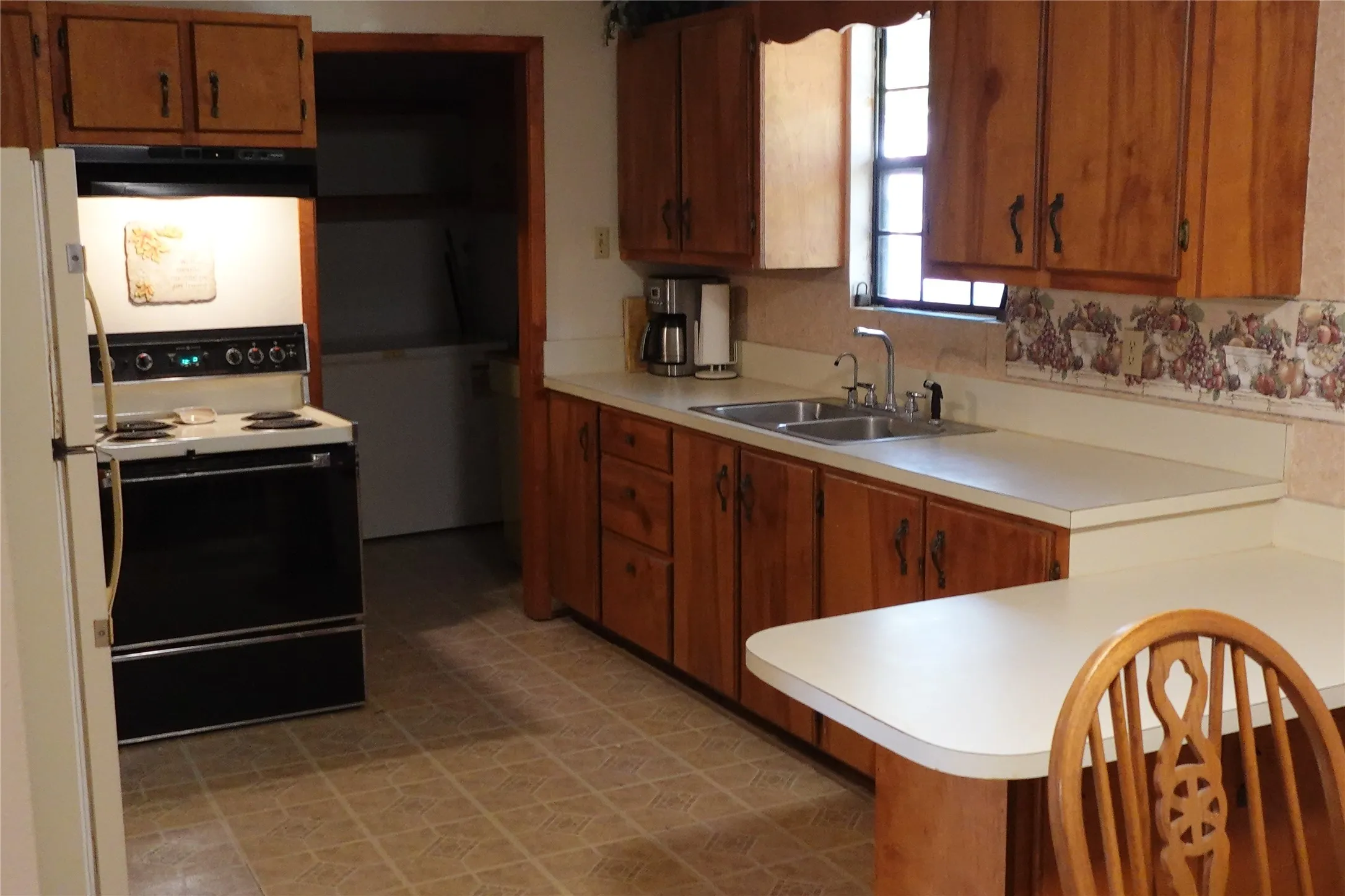 Kitchen featuring wood cabinetry, white countertops, a double basin sink, and an electric range