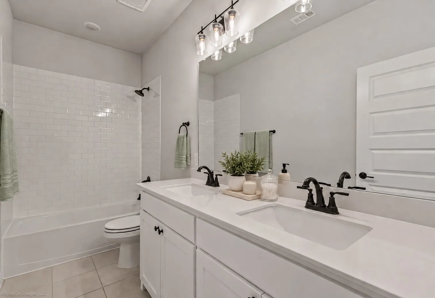 Double vanity with integrated sinks and white countertops, matte black faucets, and a three-light fixture