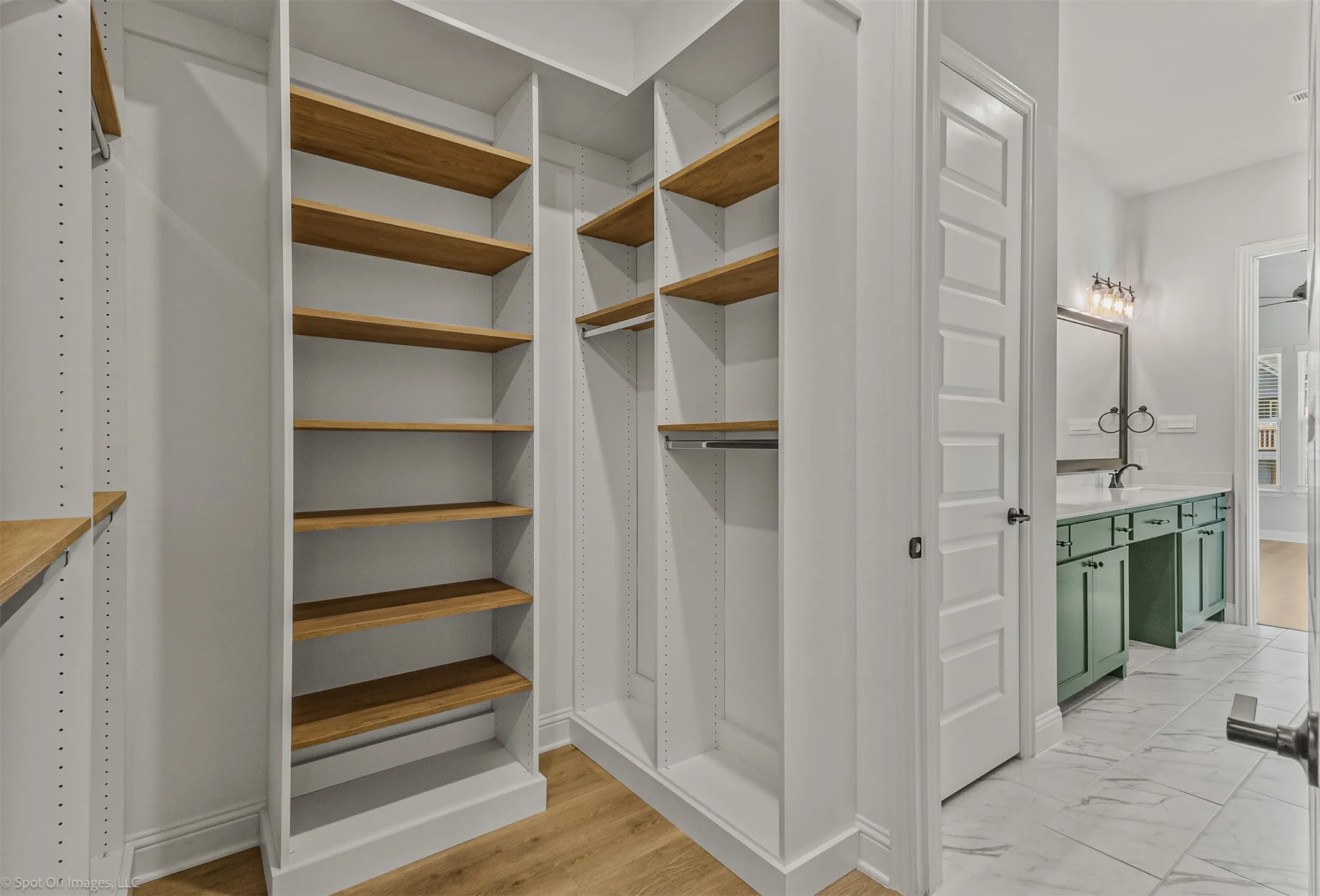 Built-in closet shelving with wood-finish shelves, hanging rods, and wood-finish flooring