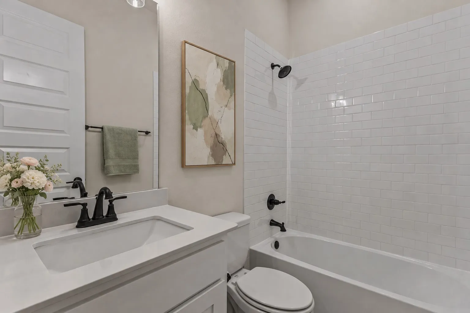 Bathroom featuring a white vanity with an integrated sink, matte black faucet, and a large mirror