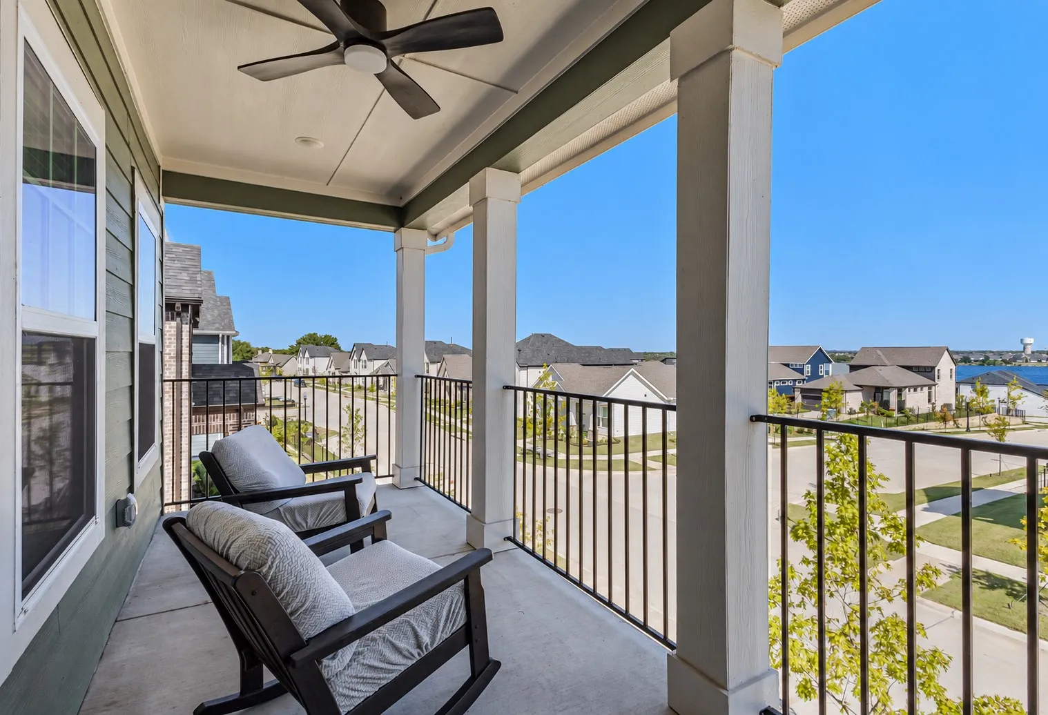 Covered balcony with a ceiling fan, concrete flooring, and black metal railings