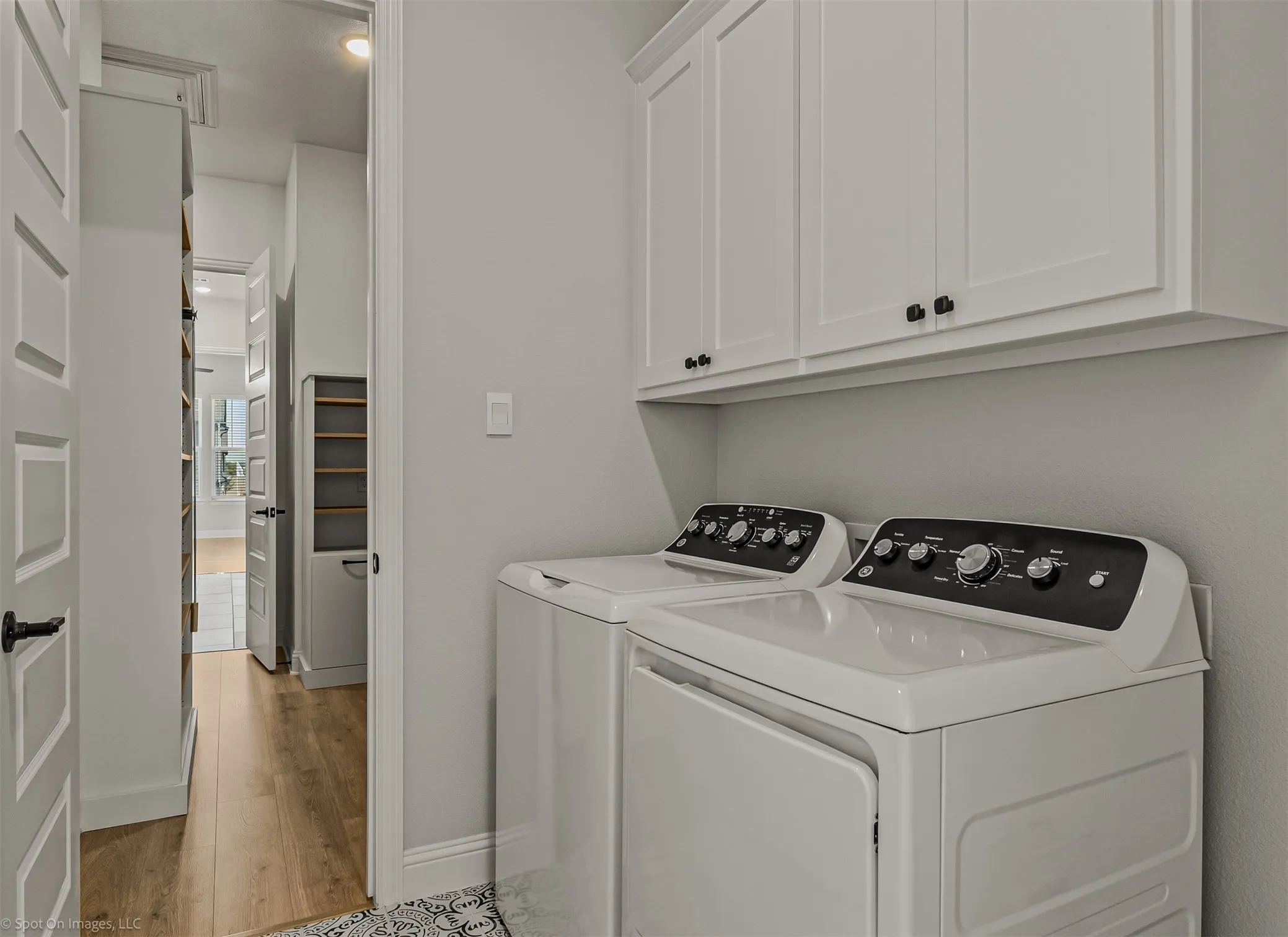 Laundry area featuring white cabinetry, black hardware, and wood-finish flooring