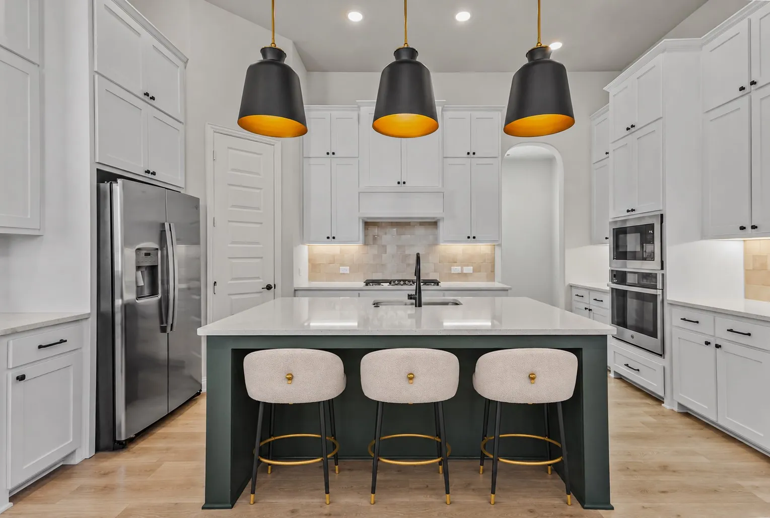 Gourmet kitchen featuring a large central island with seating, stainless steel appliances, extensive white cabinetry, recessed lighting, and wood-finish flooring