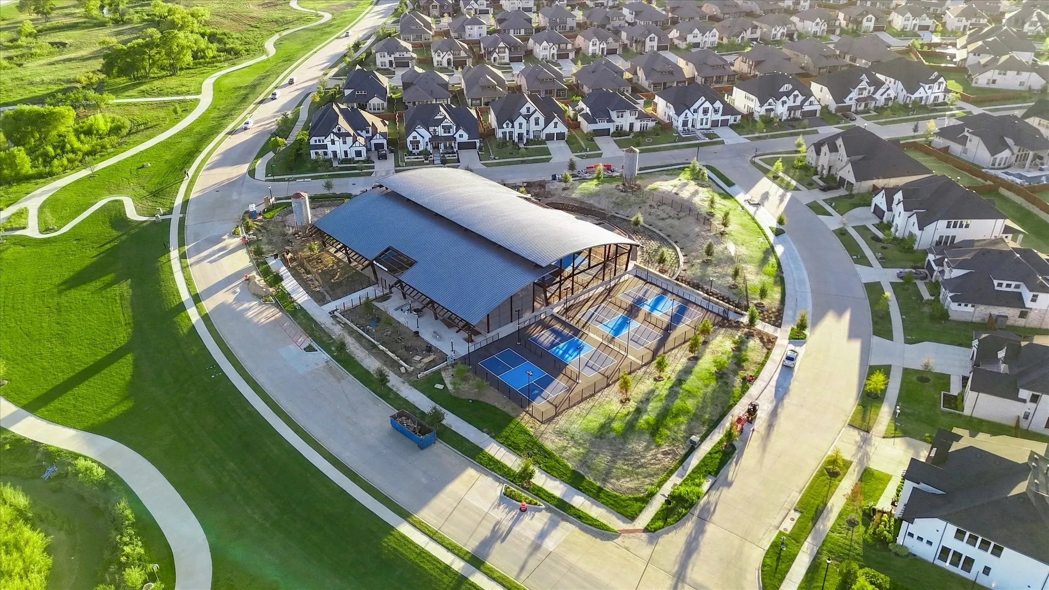 Community recreation center featuring covered courts and surrounding green spaces