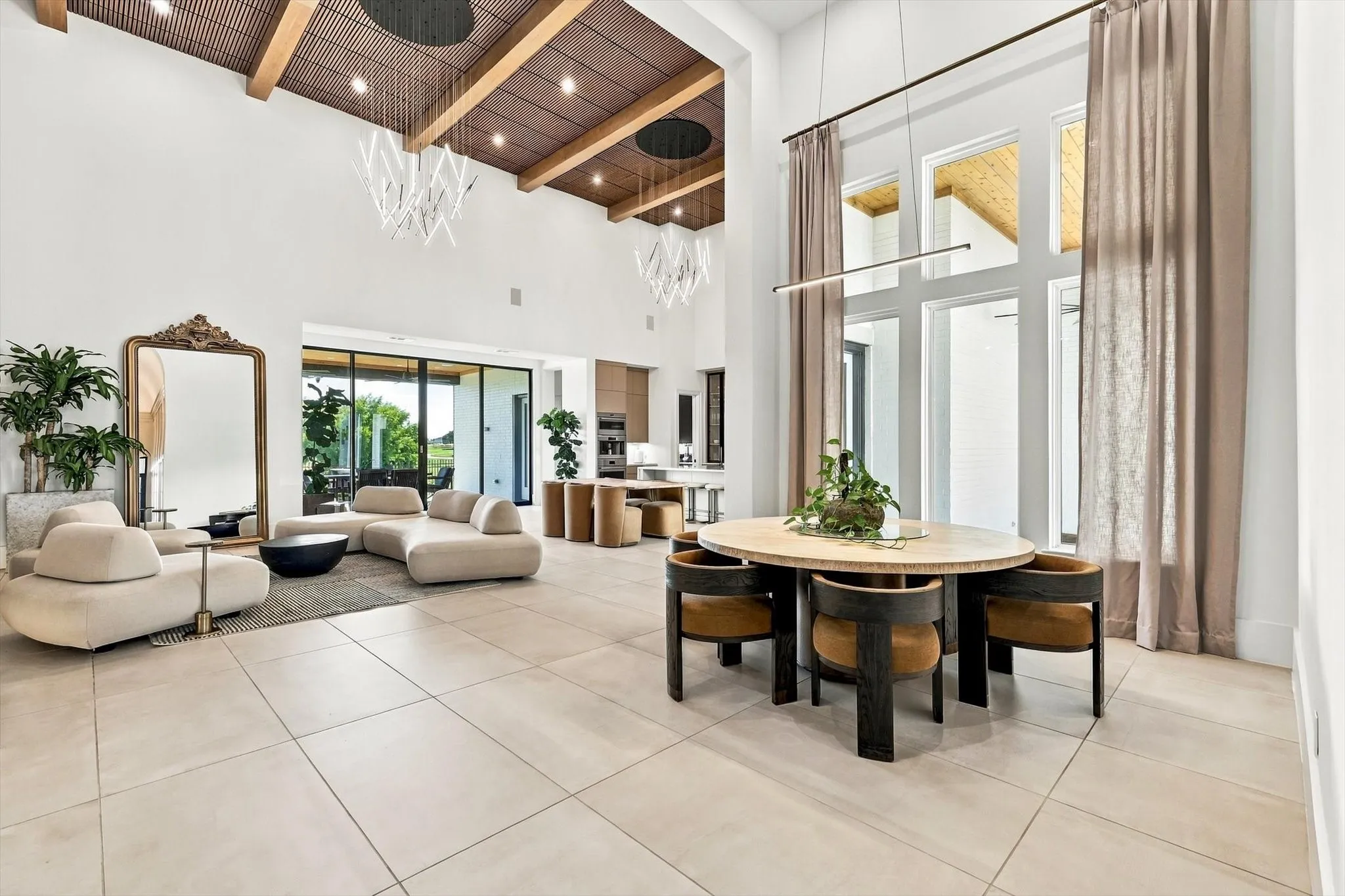 Vaulted ceilings with exposed beams, large format floor tiling, expansive window wall, linear lighting fixture, and a sliding glass door