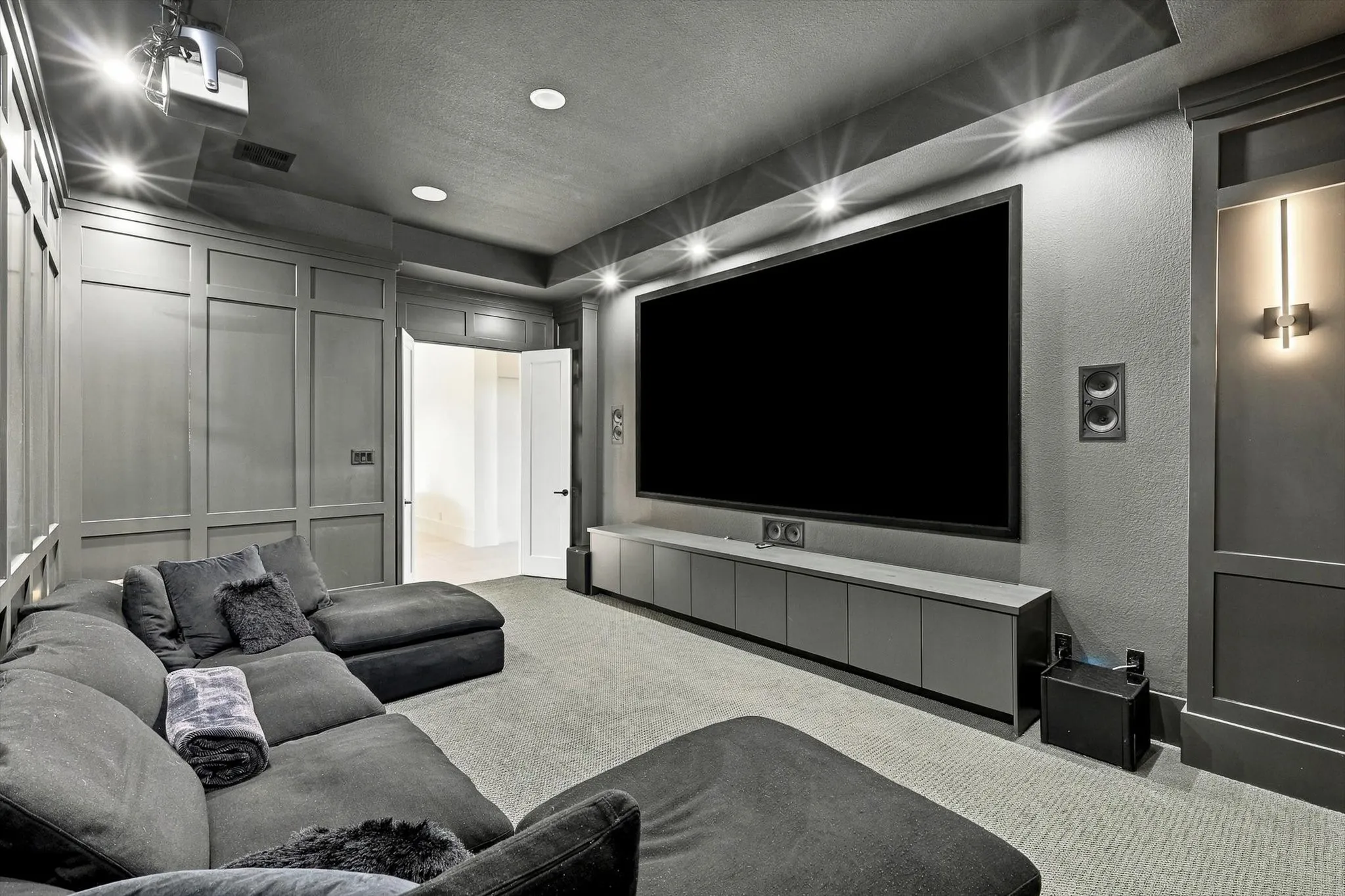Recessed lighting, large projection screen, built-in media console, wall-mounted speakers, and integrated wall paneling