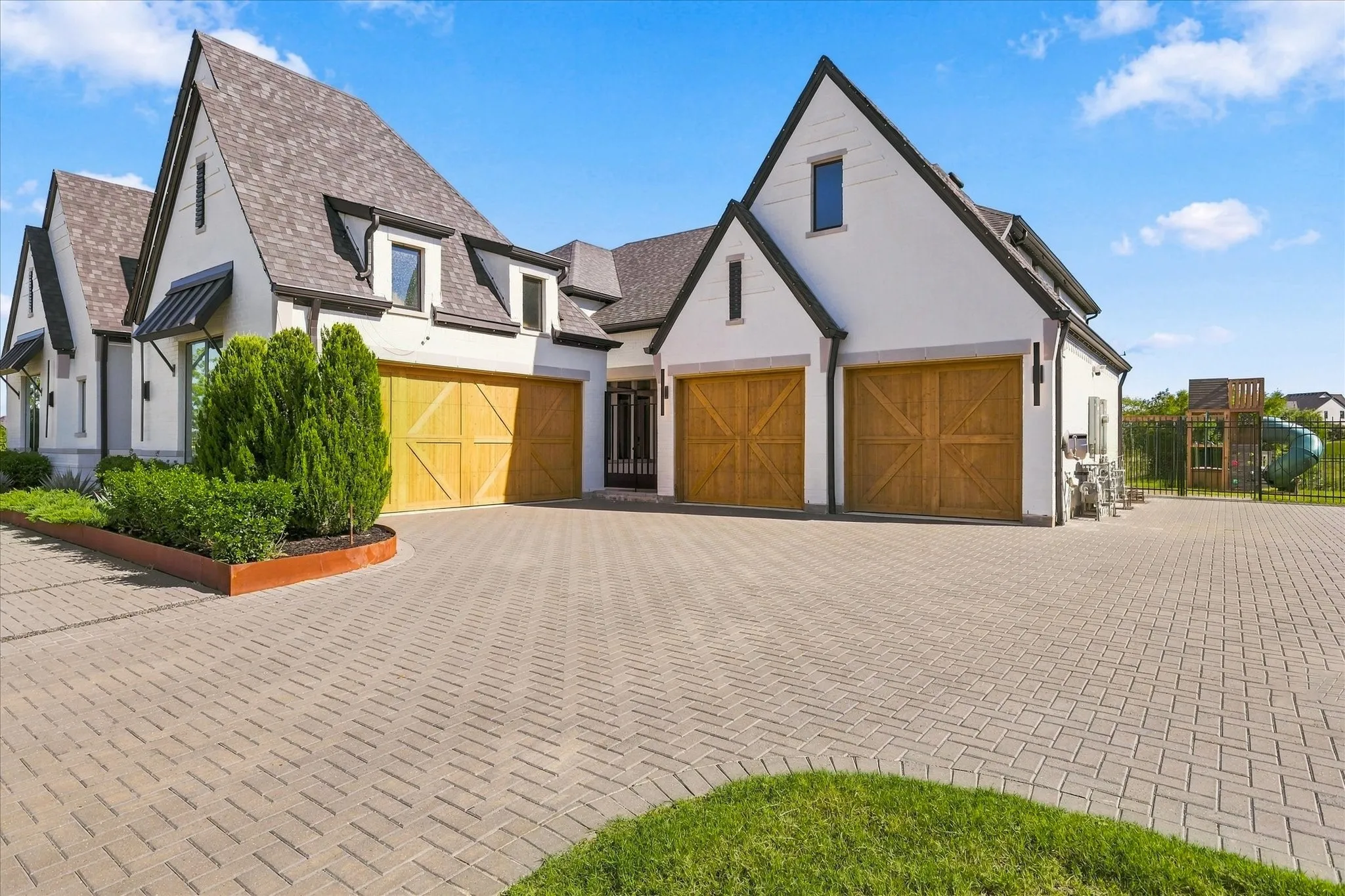 White stucco exterior with dark trim, prominent gables, and multiple dormer windows