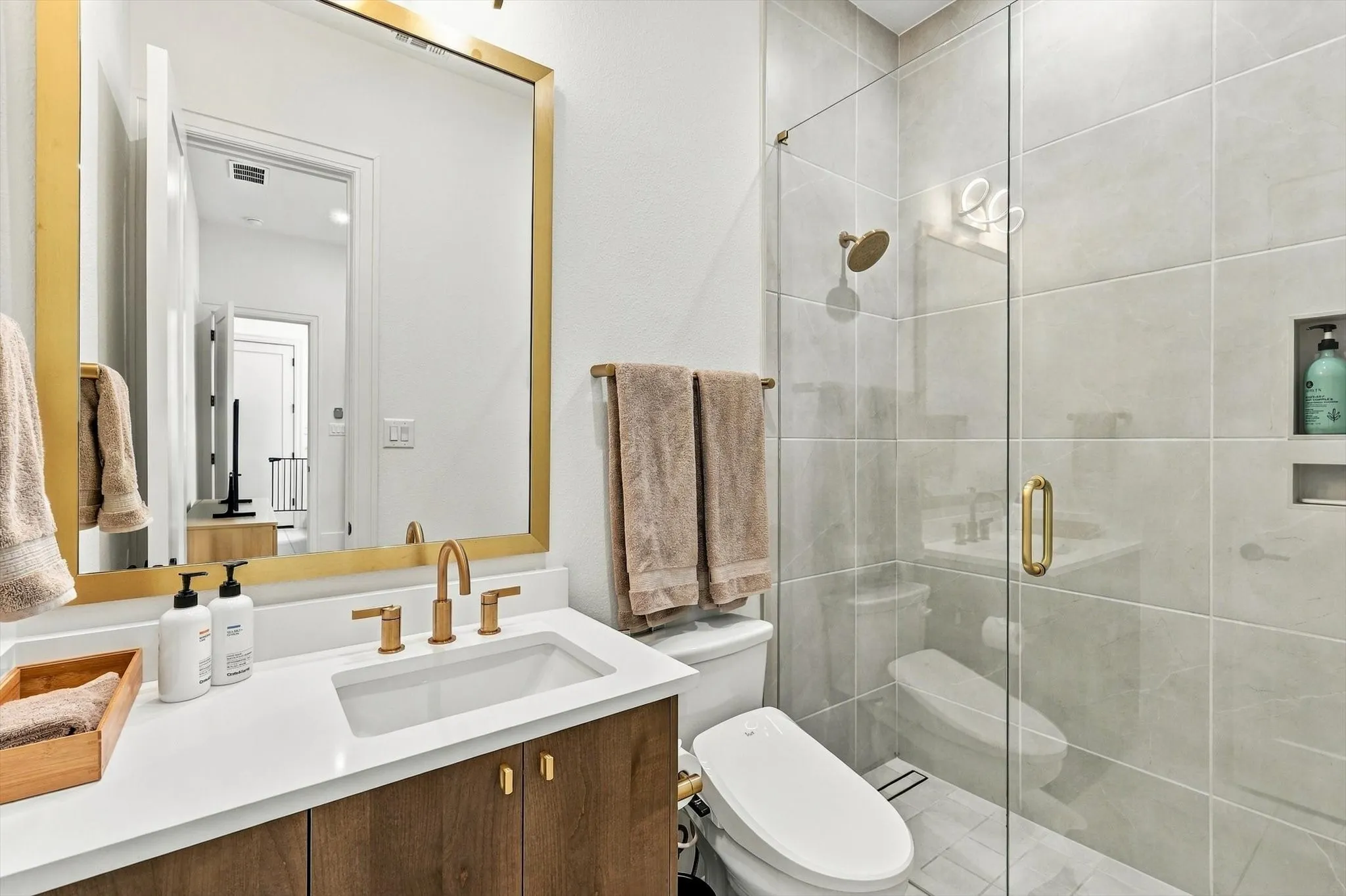Wood-finish vanity with a white countertop and gold-tone fixtures