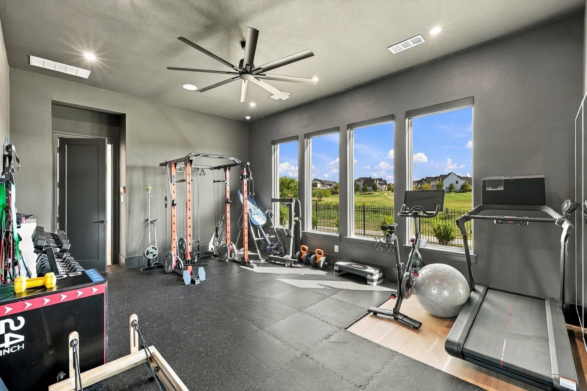 Spacious room featuring three large windows, recessed lighting, a ceiling fan, and a neutral wall color