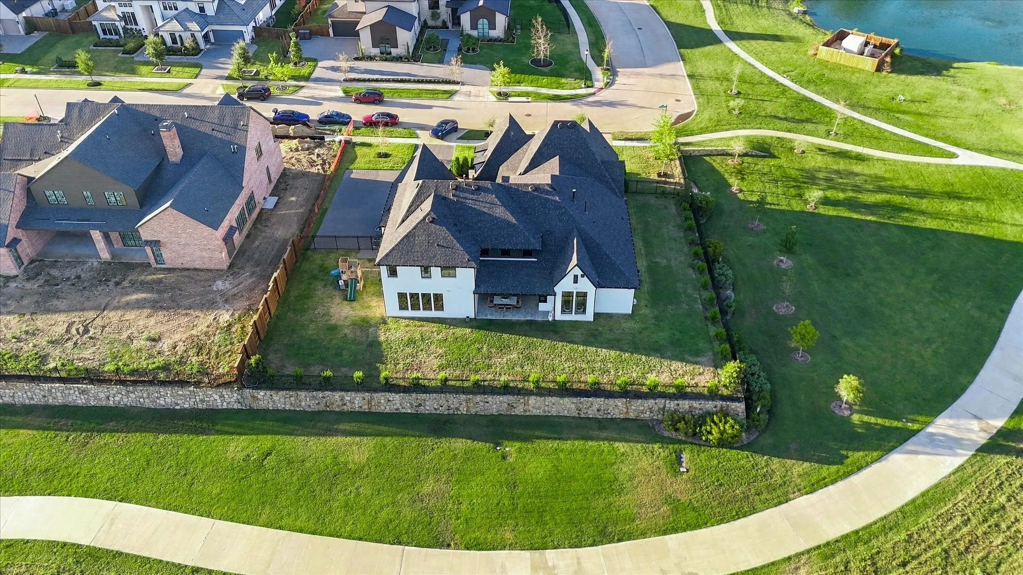 White exterior with dark roof, integrated garage, and a retaining wall with landscaping