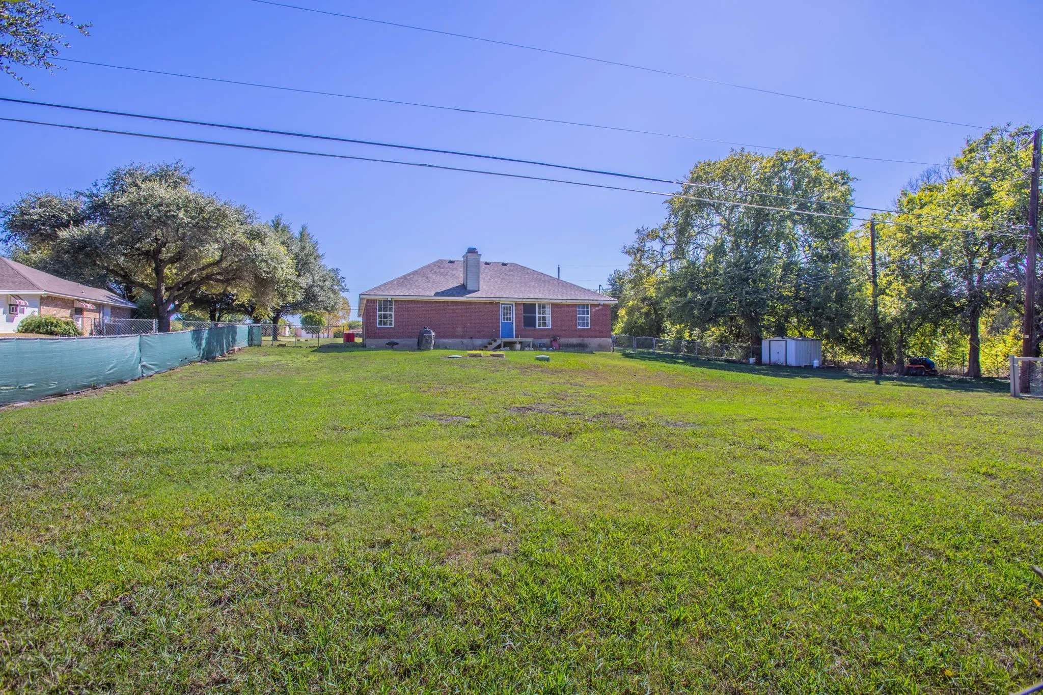 Expansive lawn with mature trees and a brick-exterior residence