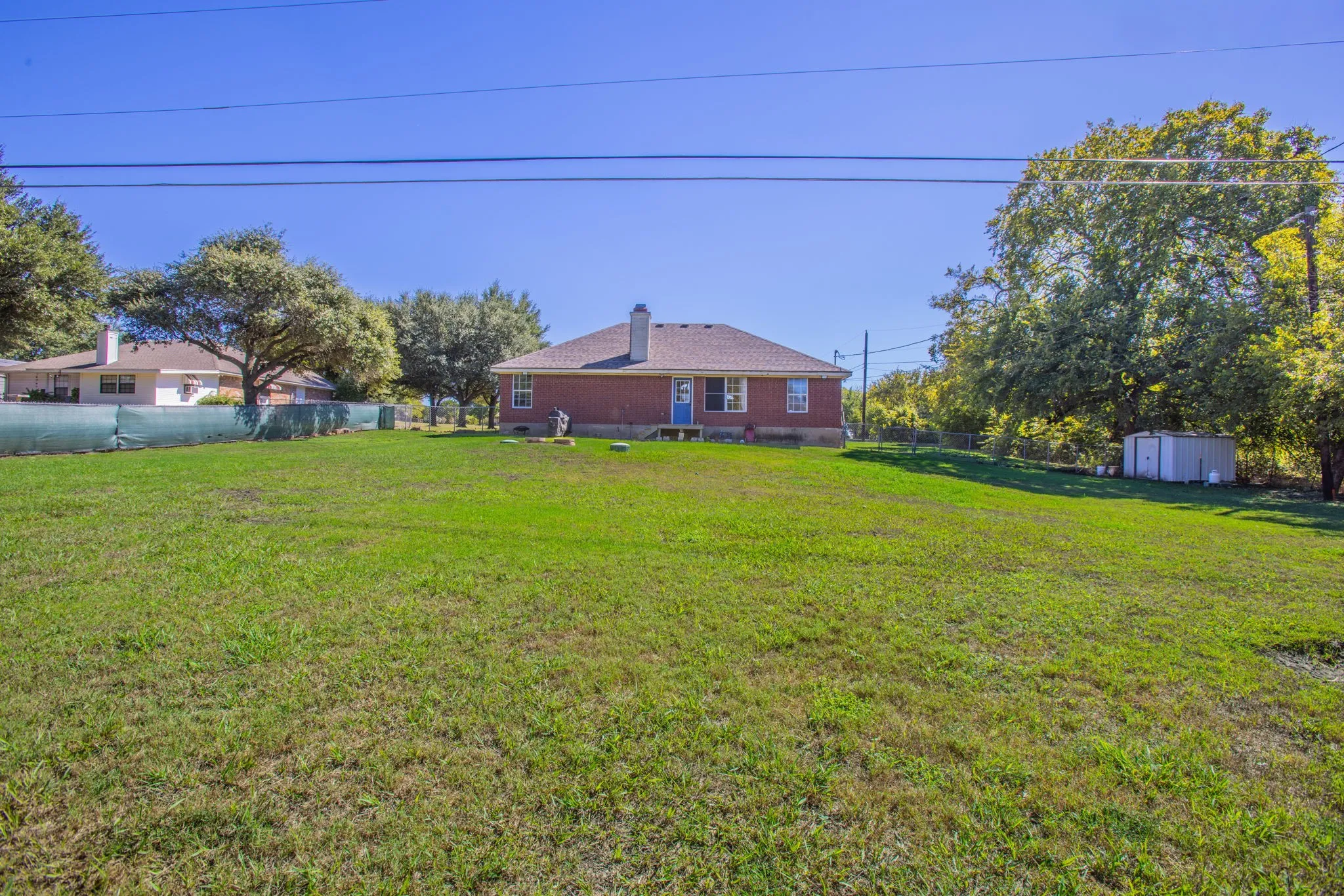 Expansive lawn with mature trees and a detached storage shed
