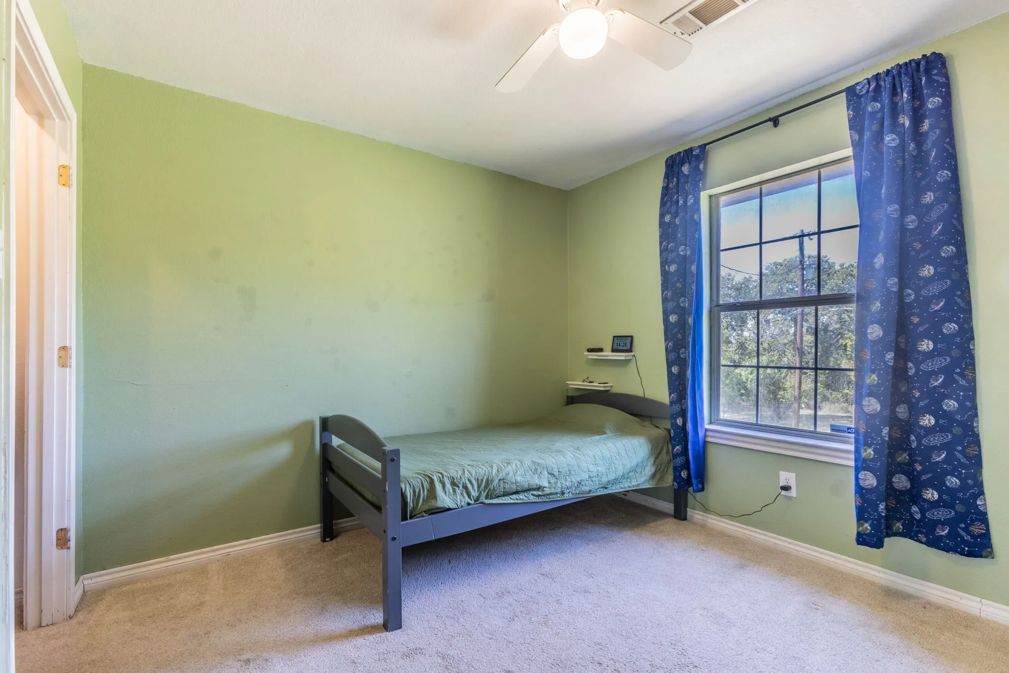 Ceiling fan with integrated lighting, window with grid panes, textured wall finish, and carpeted flooring