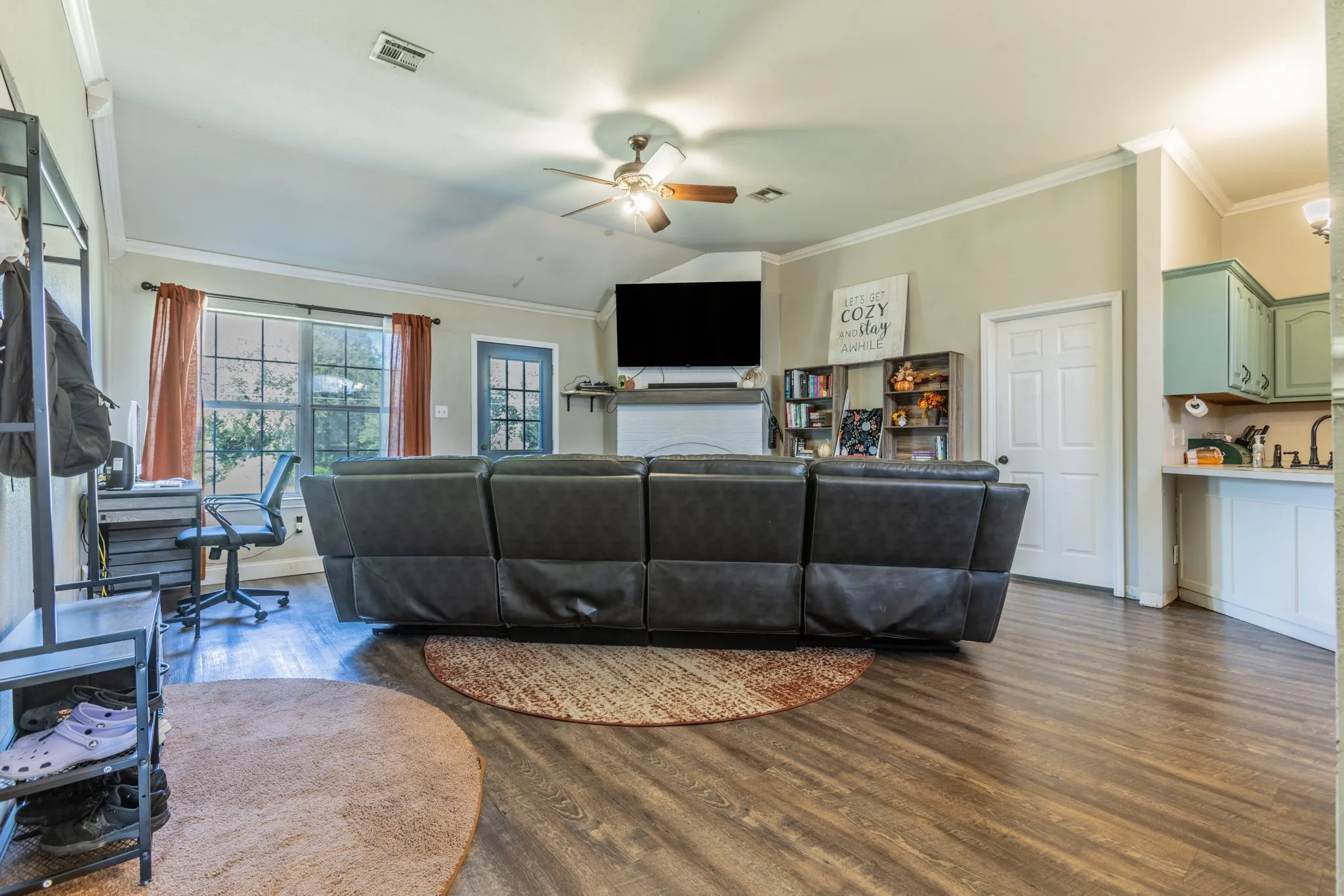 Vaulted ceiling, wood-finish flooring, ceiling fan, built-in shelving, and a built-in mantel