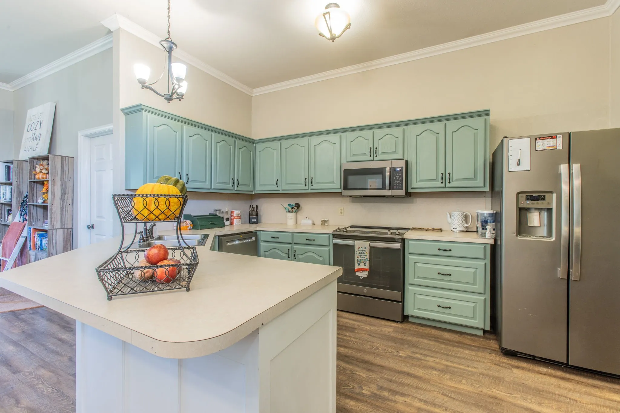 Kitchen featuring light blue cabinetry, stainless steel appliances, a center island with a light-colored countertop, and wood-finish flooring