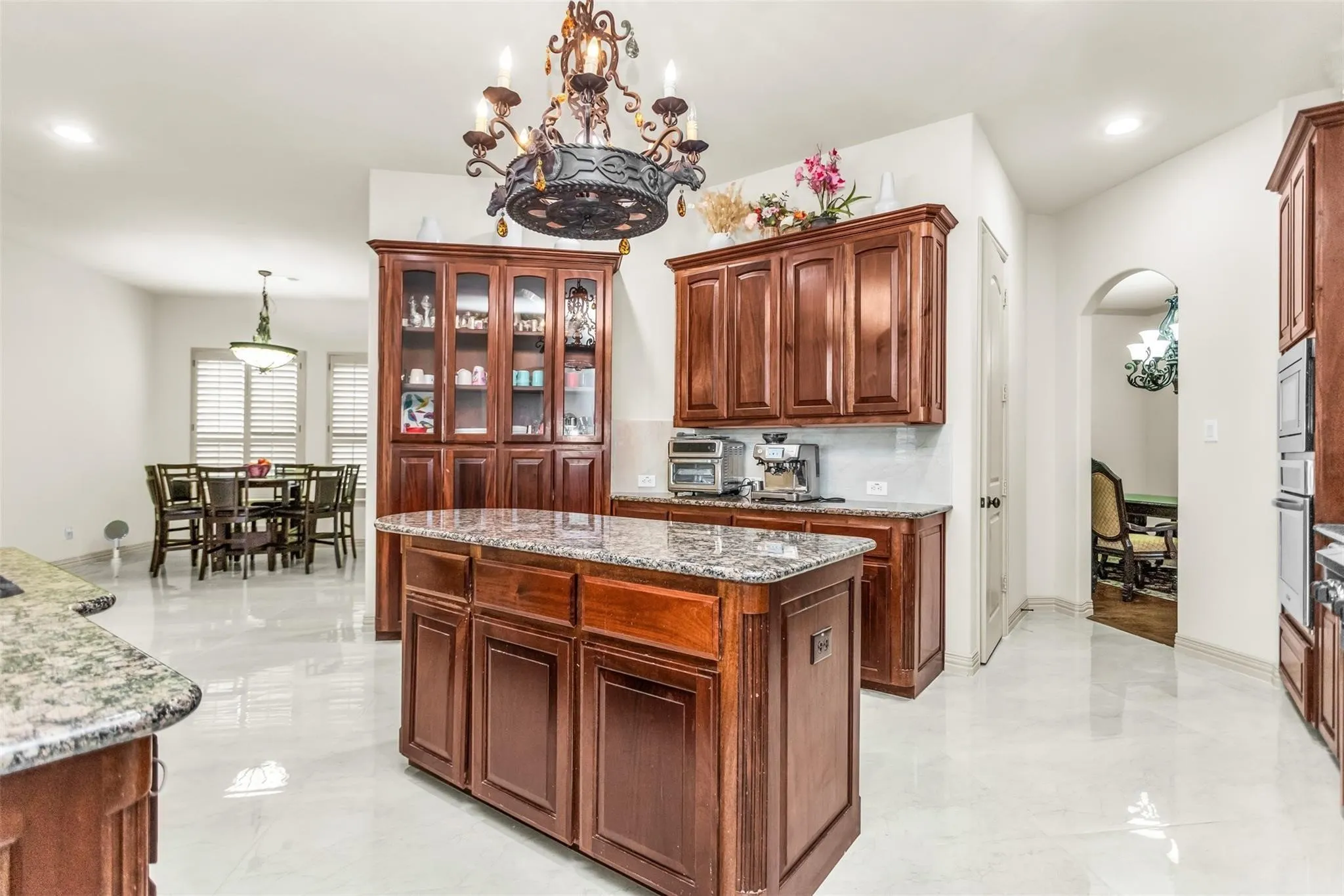 Kitchen featuring a central island with a stone countertop, rich wood-finish cabinetry, and polished tile flooring
