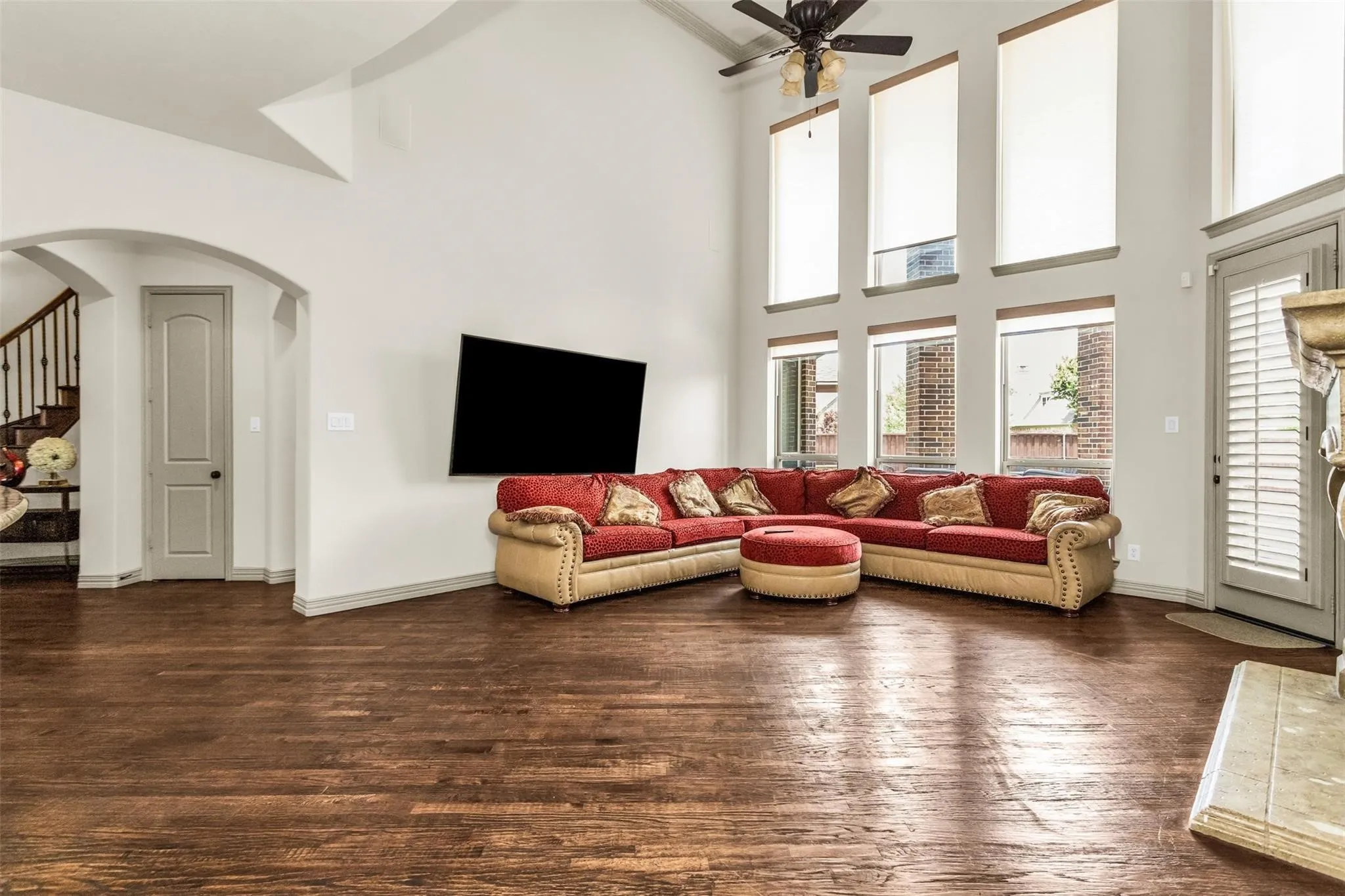 Two-story living area with wood-finish flooring, soaring ceilings, and multiple windows with roller shades