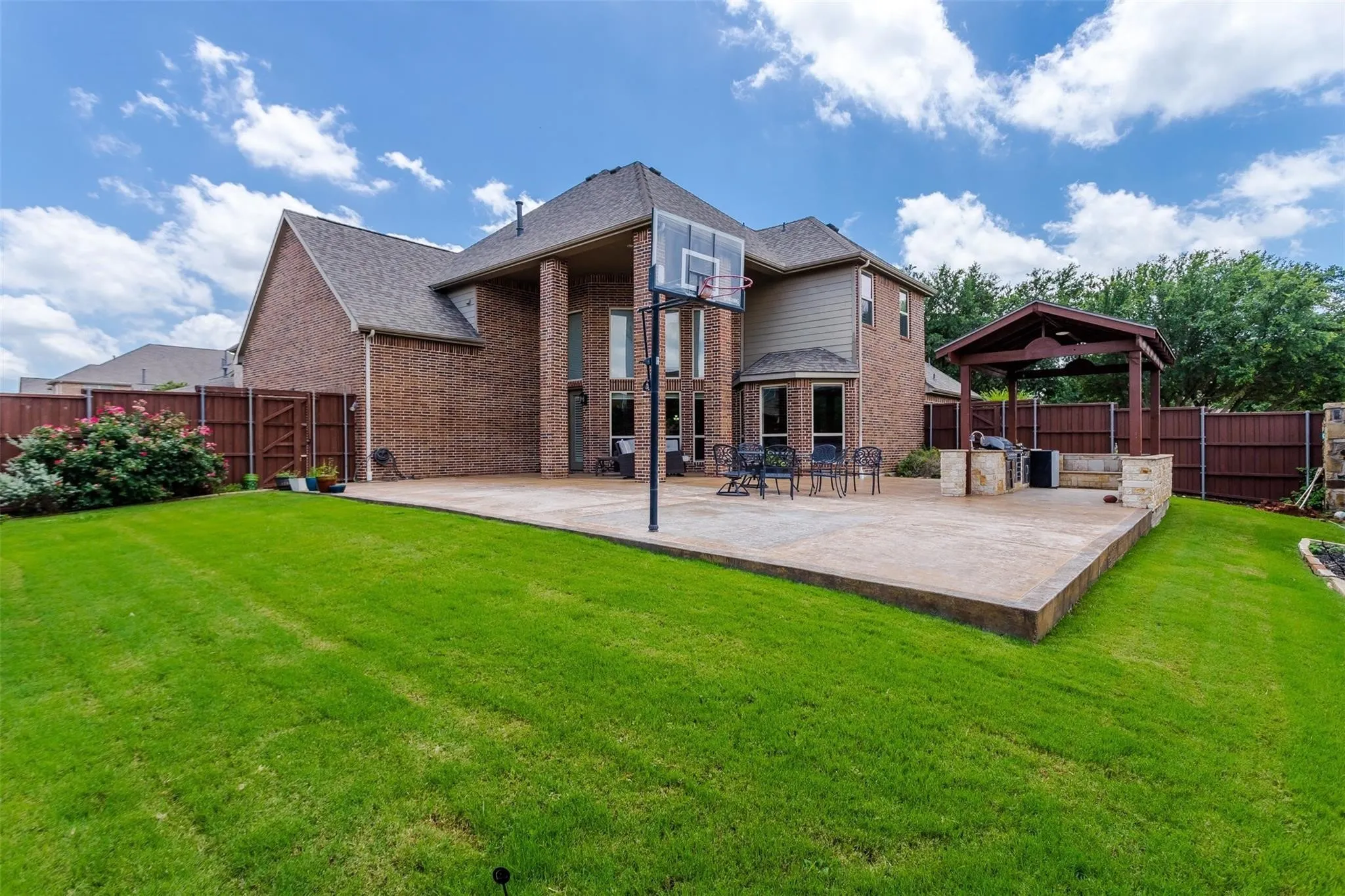 Brick exterior with multiple windows, leading to an expansive concrete patio