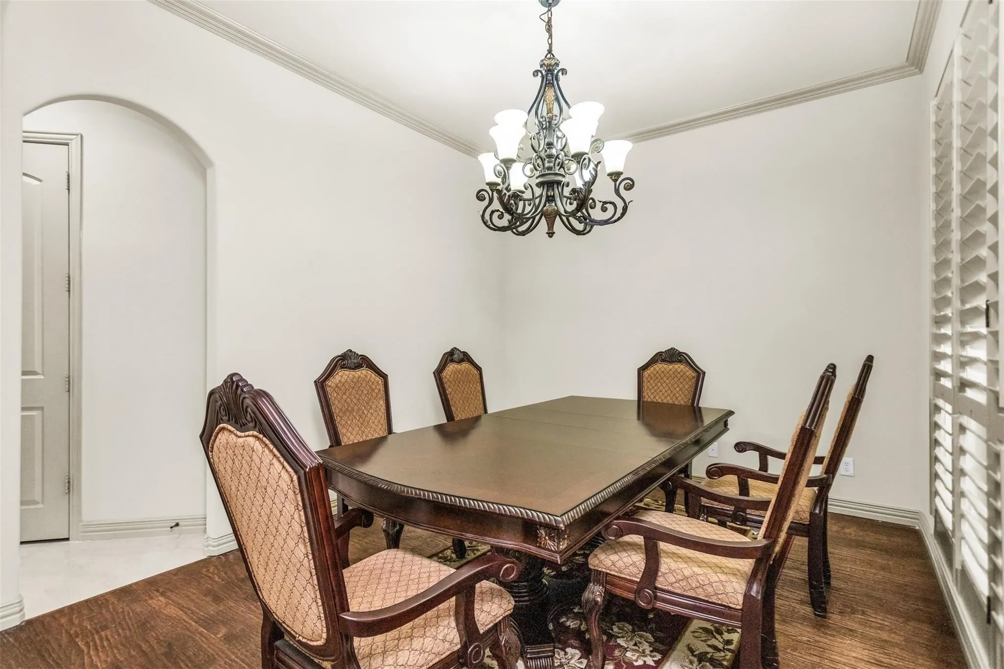 Wood-finish flooring, crown molding, and an arched doorway