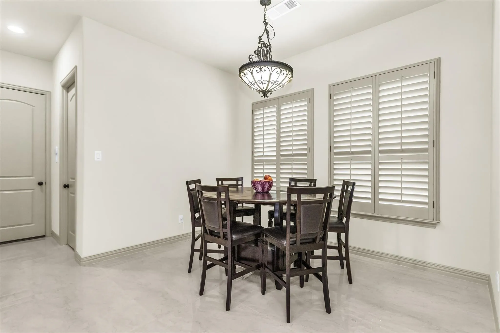 Light-toned walls, arched interior door, tile flooring, interior plantation shutters, and a decorative chandelier