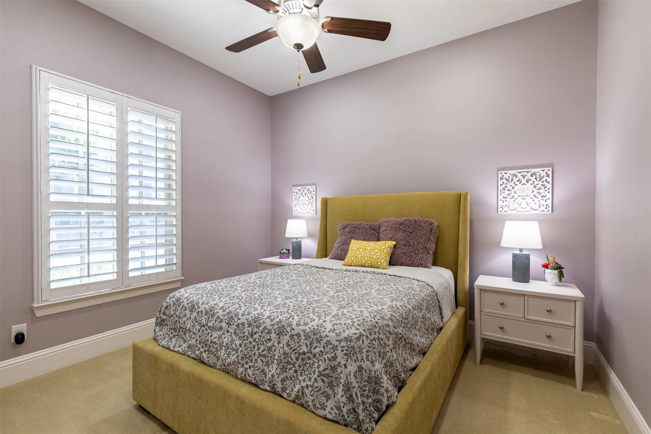 Downstairs guest suite with ceiling fan and plantation shutters.