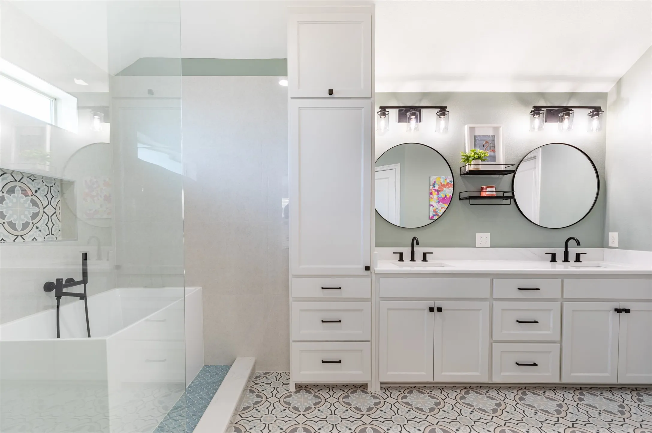 En-suite bath with dual sinks and linen cabinetry.