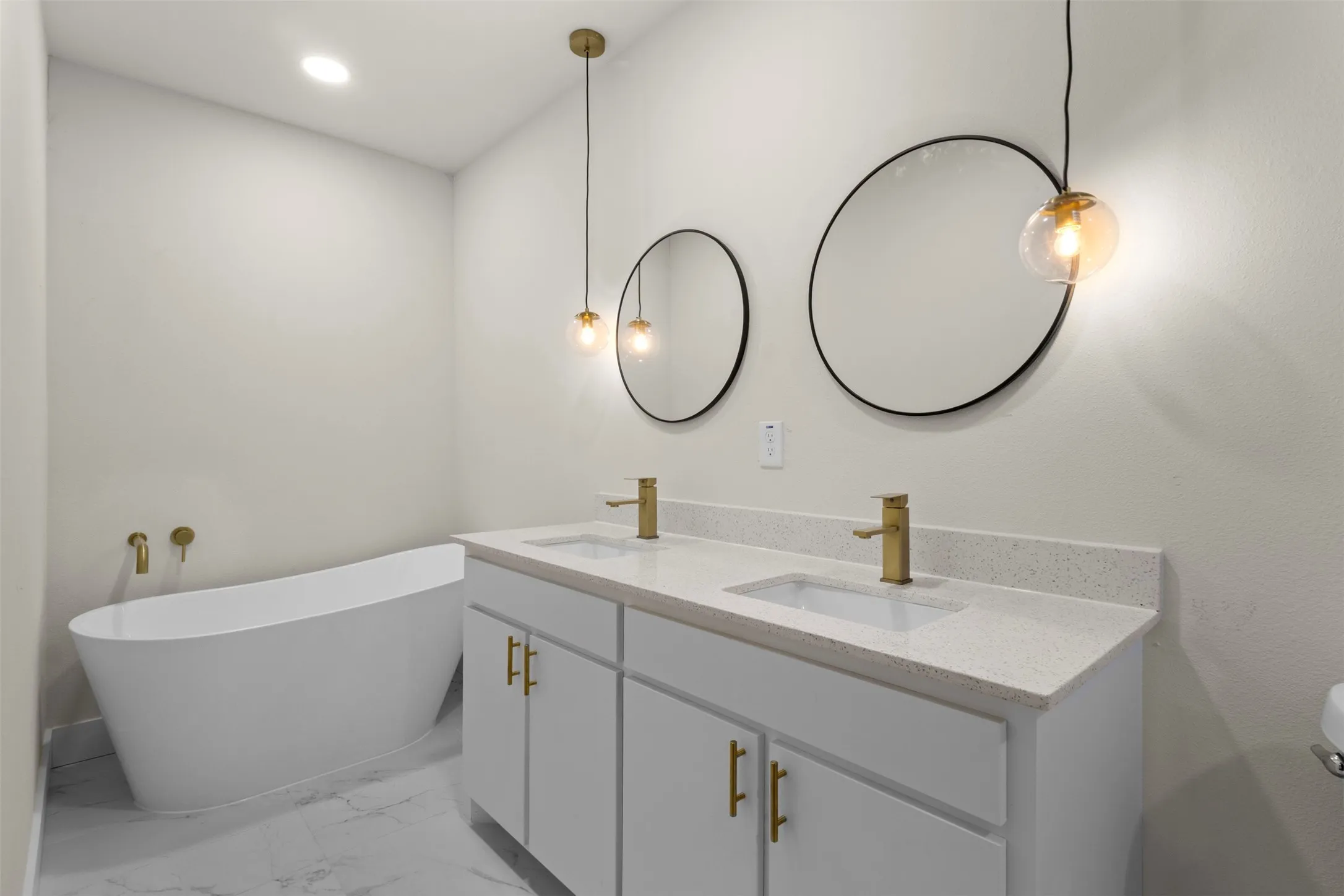Double vanity with quartz countertop, dual undermount sinks, and gold-finish fixtures