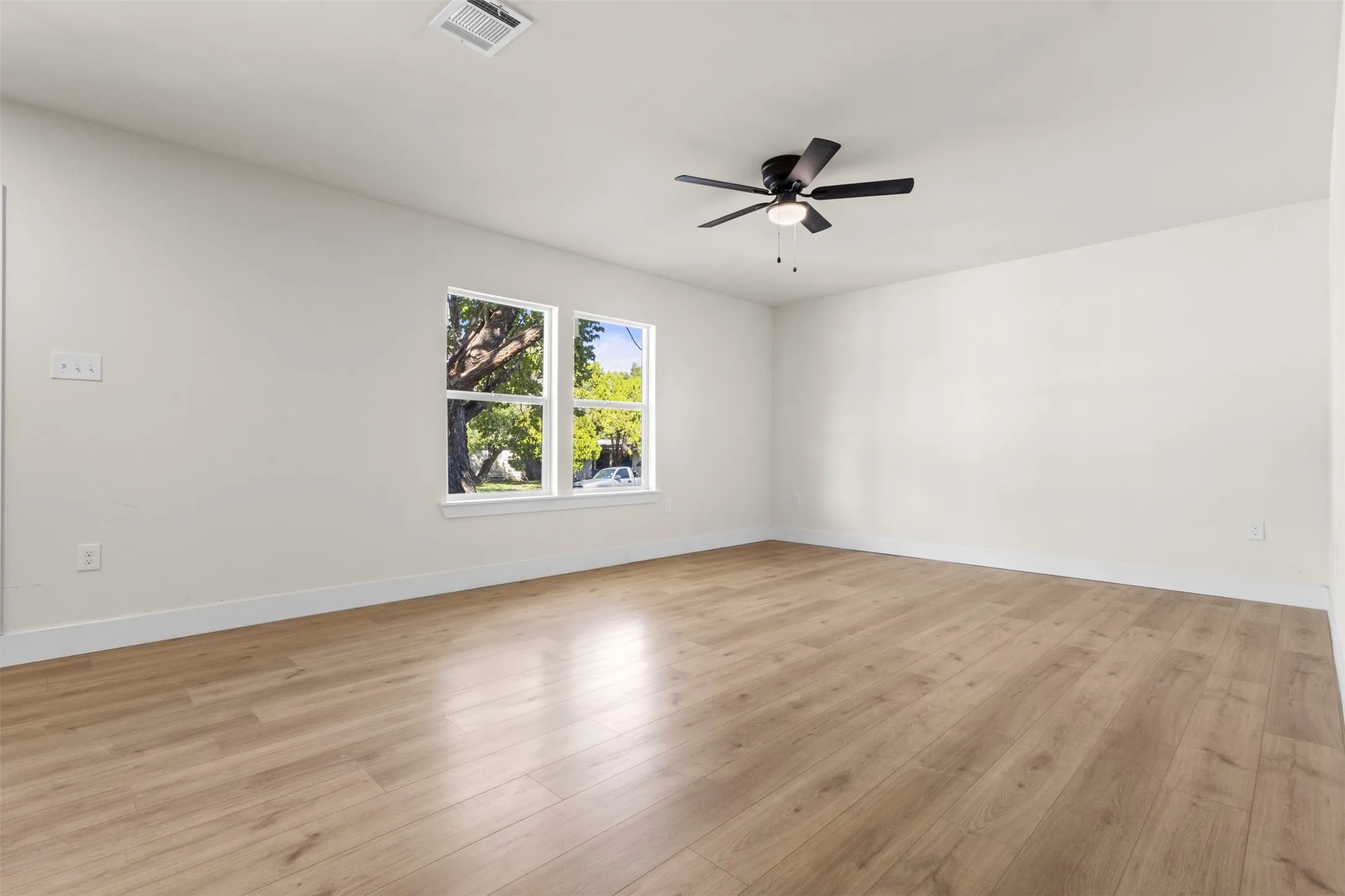 Wood-finish flooring, white walls, and a ceiling fan with integrated lighting