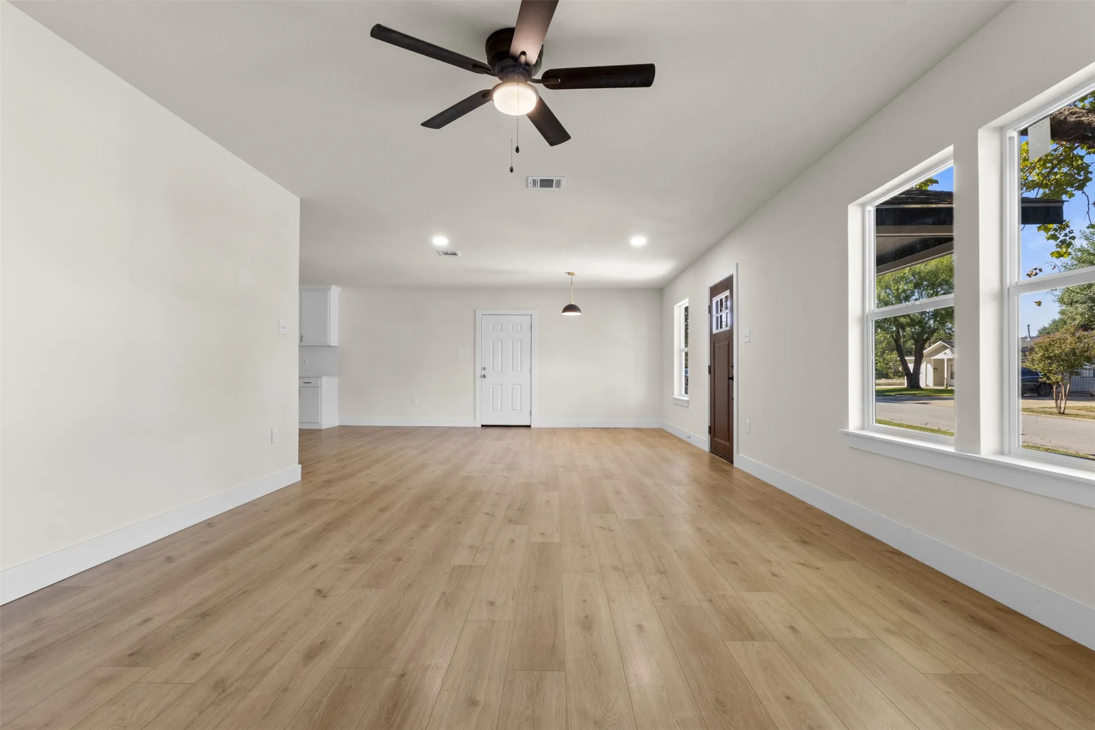 Wood-finish flooring throughout, bright white walls, recessed lighting, and multiple windows with white trim