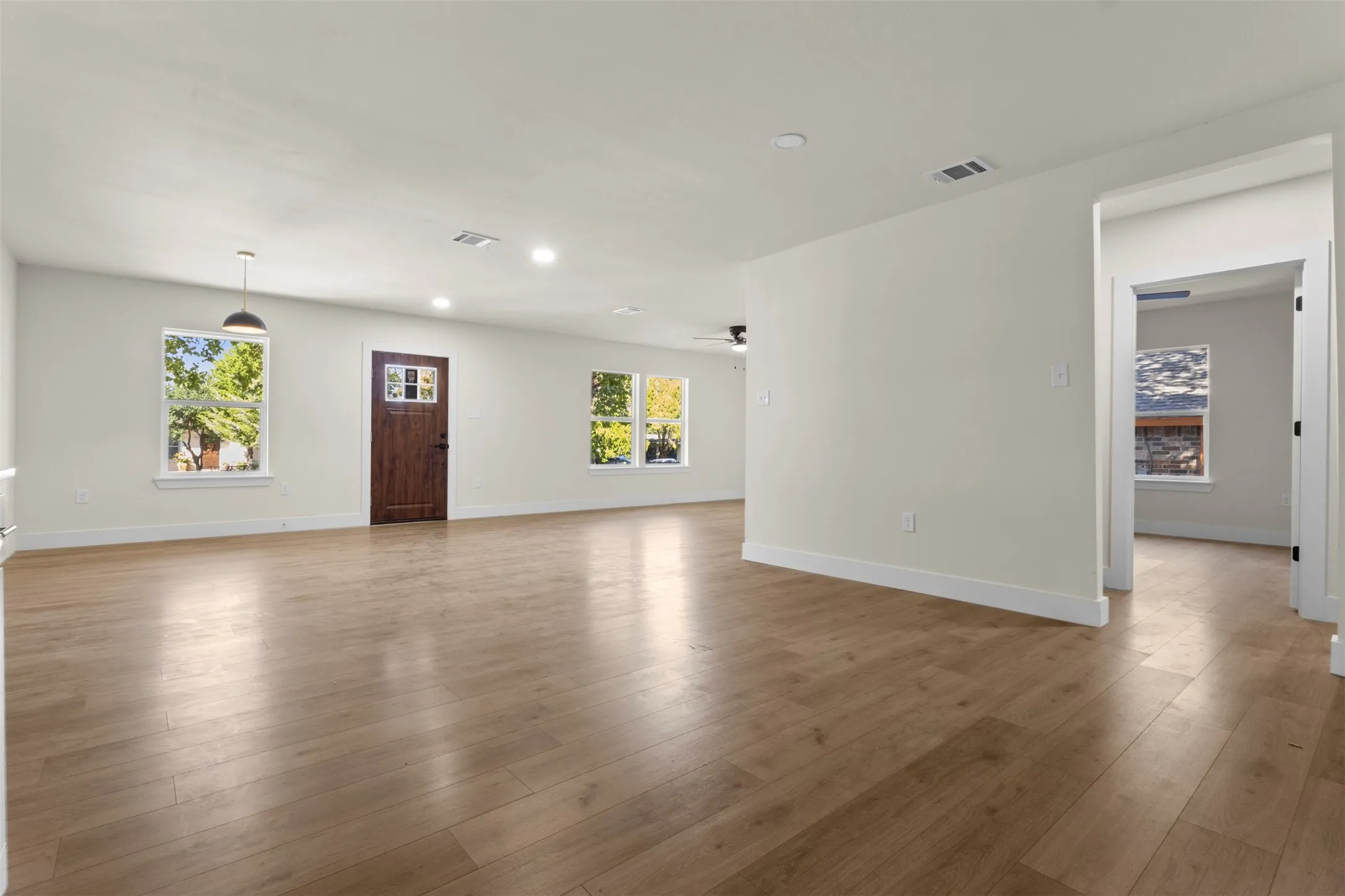 Expansive room with wood-finish flooring, recessed lighting, and multiple windows