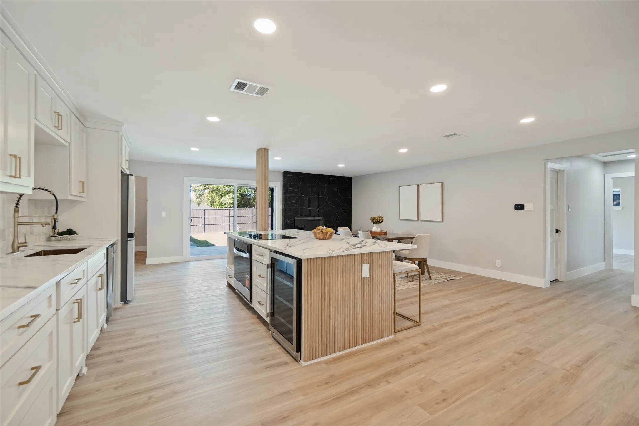 Open-concept living space with light wood-finish flooring, recessed lighting, and white cabinetry
