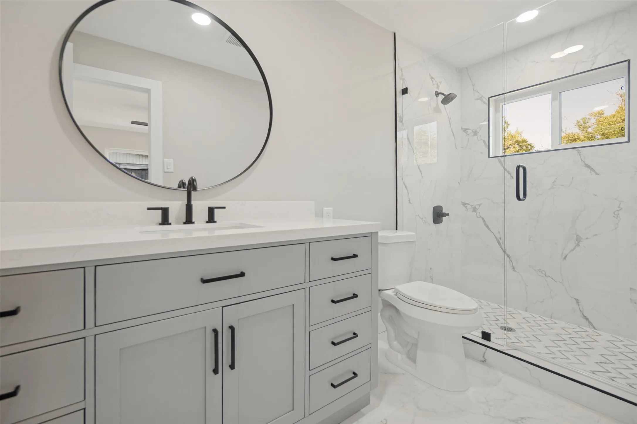Floating vanity with a quartz countertop, circular mirror, and matte black fixtures